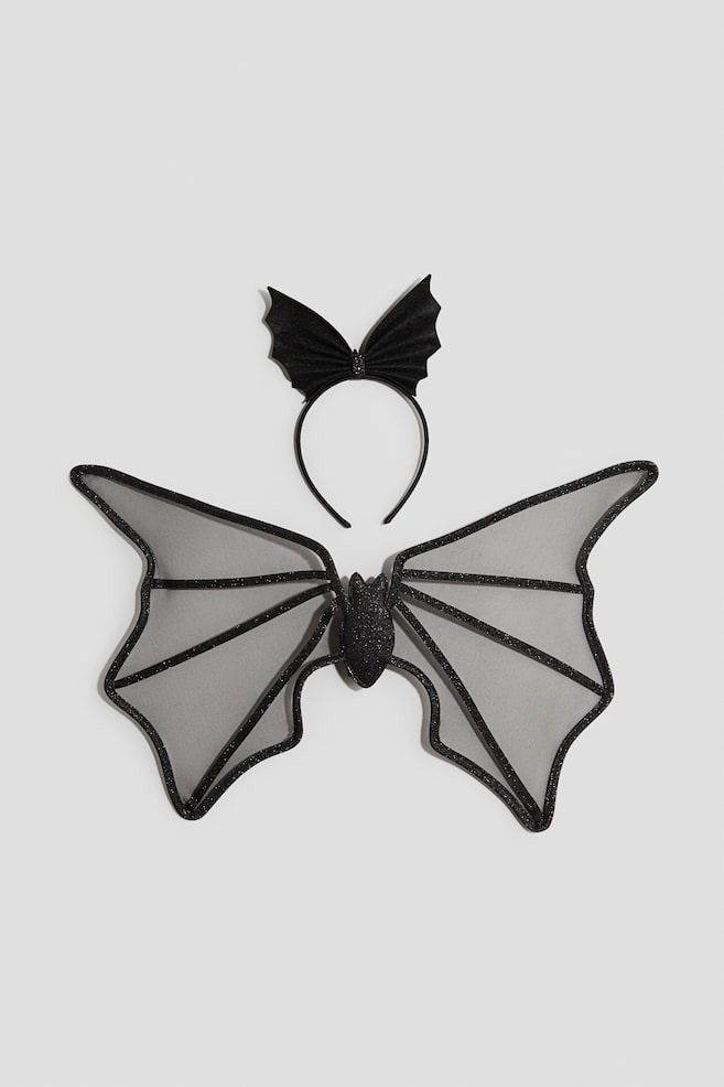 A black bat costume set is displaying from the front, featuring a pair of sheer, greyish-black mesh wings with glittery black ribbing and borders, alongside a matching black headband adorned with a bat-wing-shaped bow. - 1