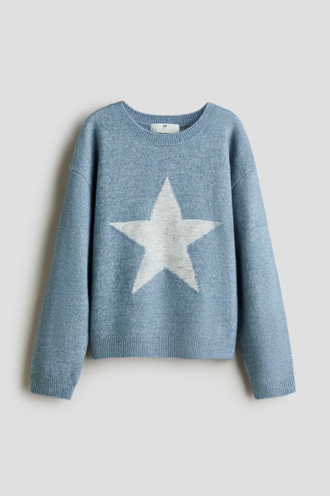 Se muestra un jersey de punto azul claro visto de frente, con un gran diseÃ±o de estrella blanca centrado en el pecho. El jersey de corte holgado presenta cuello redondo acanalado, hombros caÃ­dos y acabados acanalados en los puÃ±os y el bajo. - 1