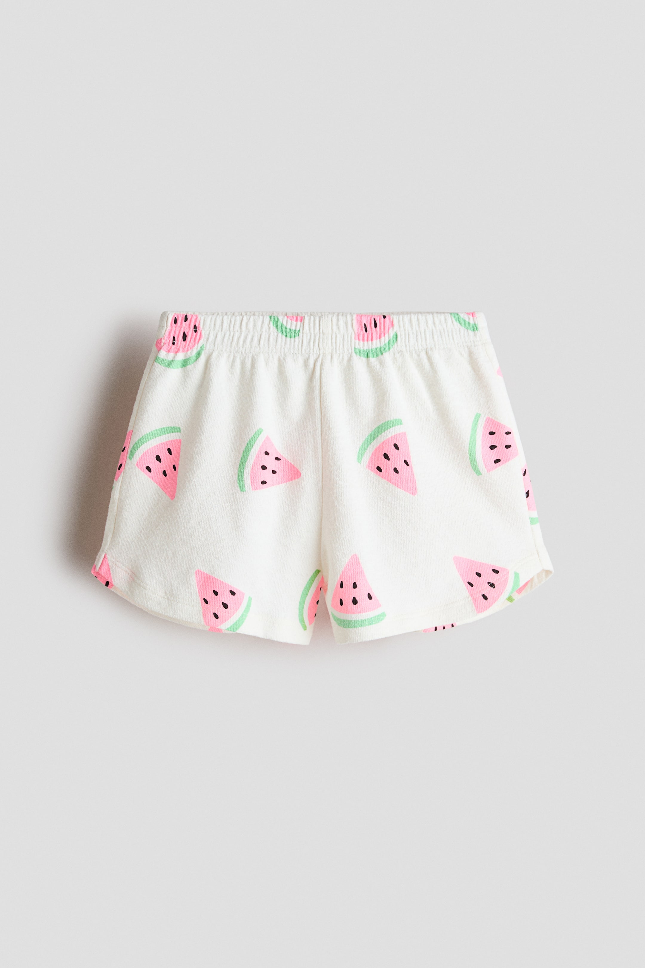 View larger image: These shorts showcase an all-over watermelon print on a white textured knit fabric. They're crafted with an elasticated waistband and slightly curved hems.