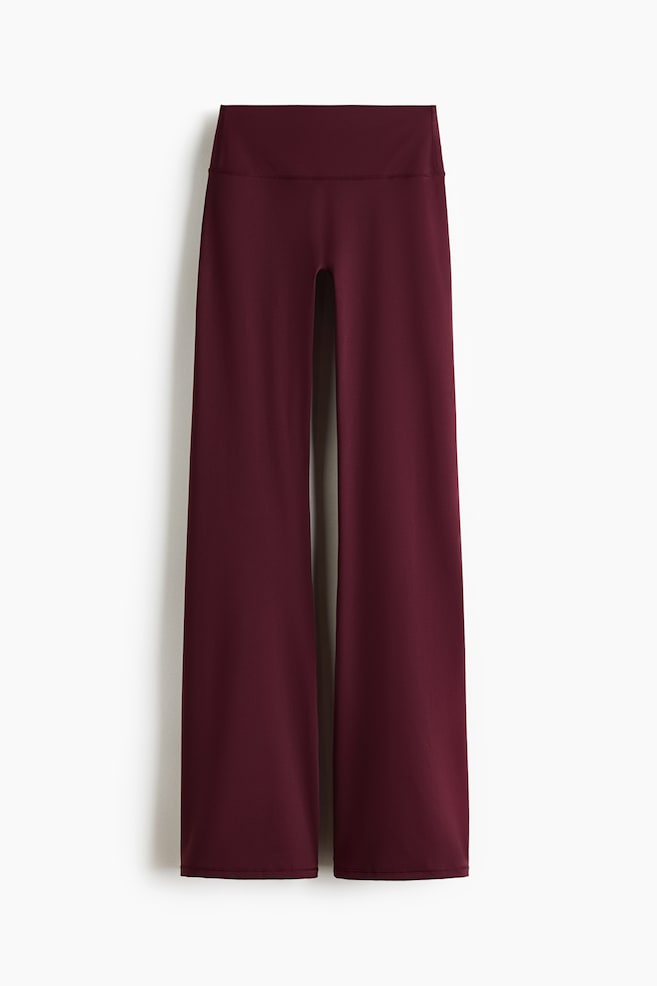 SculptMove Flared sports leggings showcase a rich maroon hue. They feature a wide, high-rise waistband and a sleek, flared leg design, presented laid flat from the front. - 1