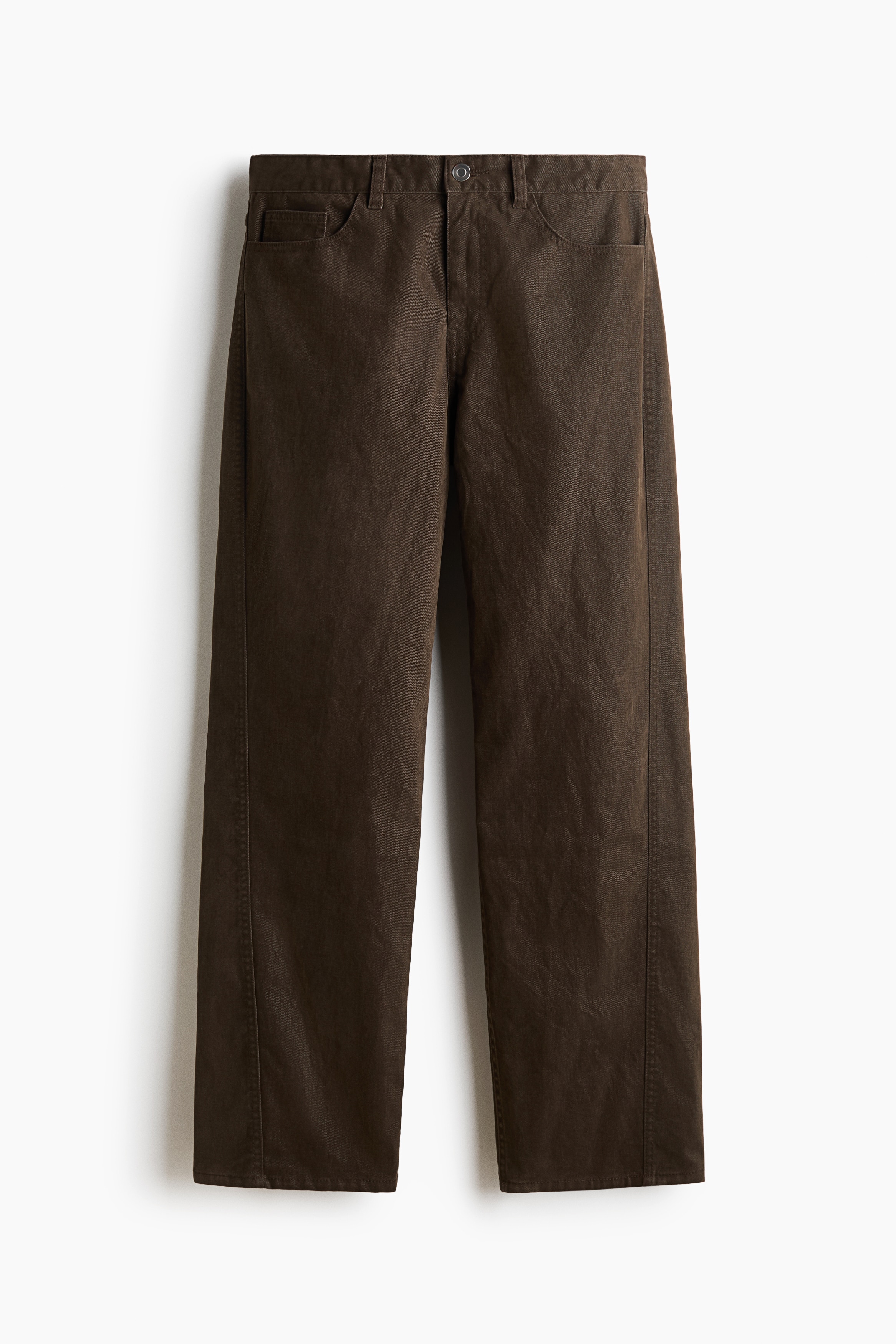 Brown cotton twill trousers featuring a relaxed fit, straight legs, and forward-facing side seams are worn by the model. The trousers are paired with a cream-coloured knit henley jumper and brown boots.
