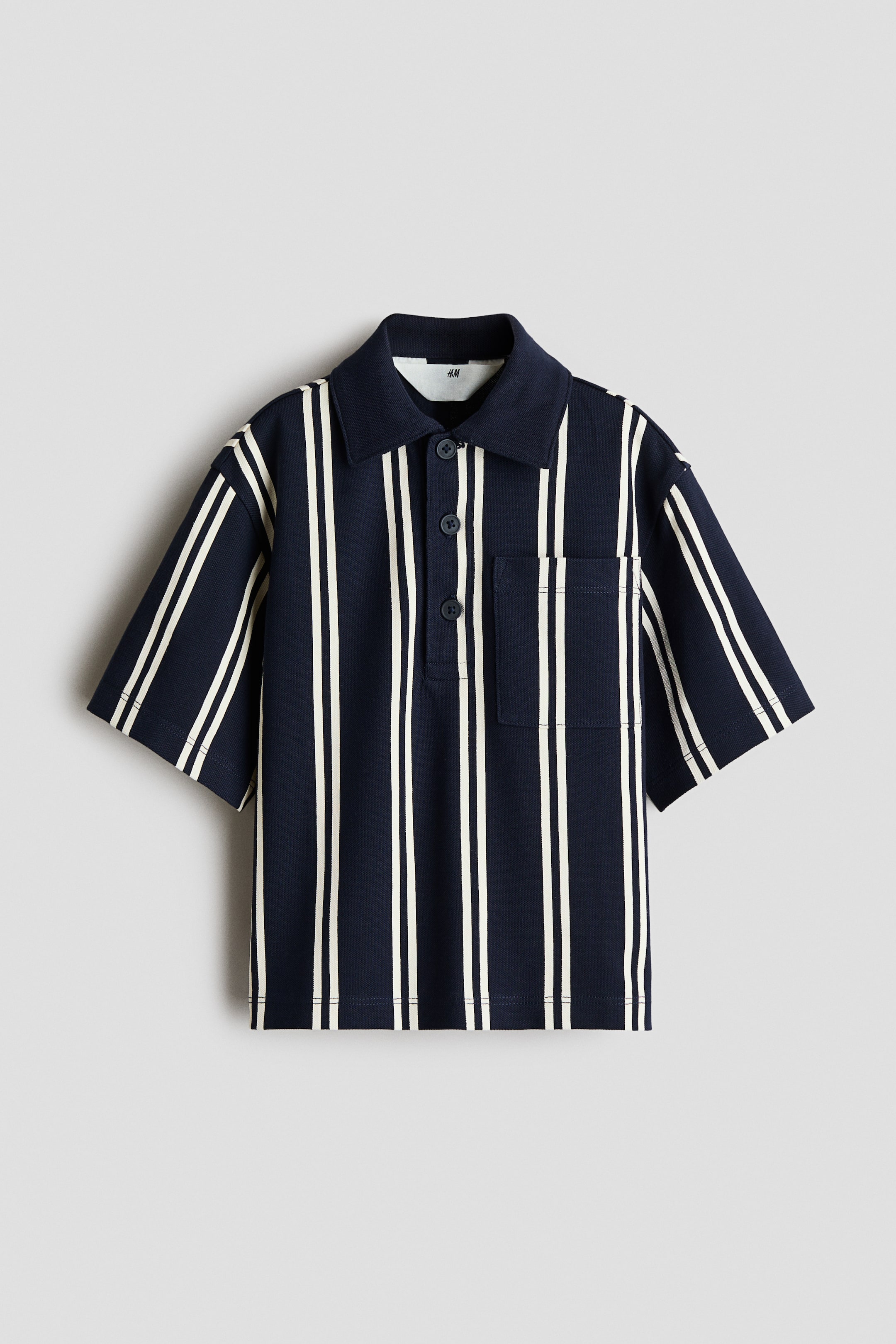 View larger image: A navy blue short-sleeve polo shirt features white vertical stripes, a pointed collar, a three-button placket, and a patch pocket on the left chest.