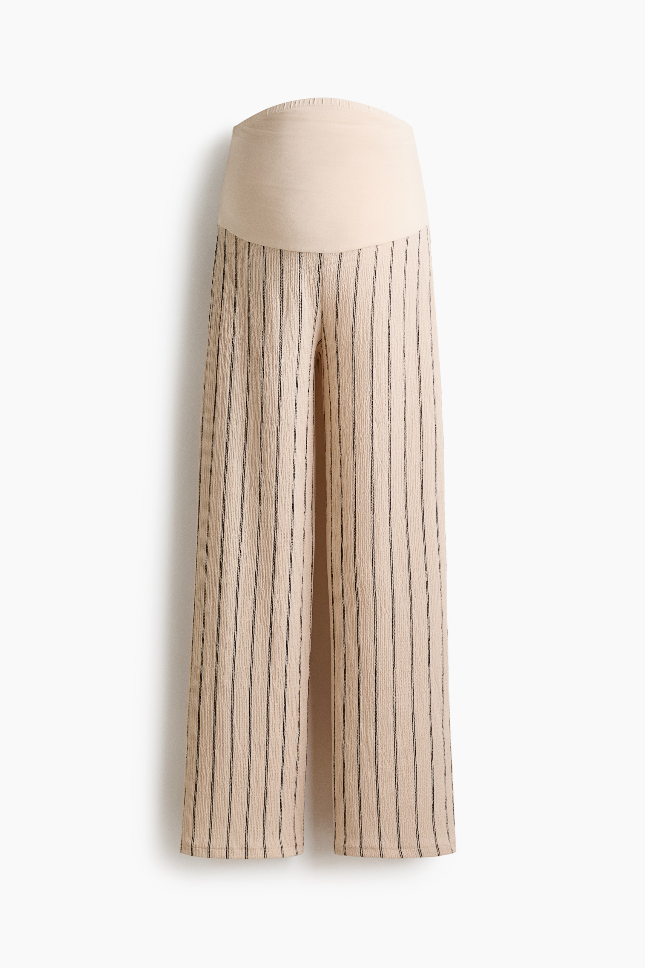 View larger image: Wide pants in light beige with black vertical stripes are shown from the front. They feature an allover crinkled texture and are designed with a high, wide, solid beige waistband, finished with fine pleating along the top edge.