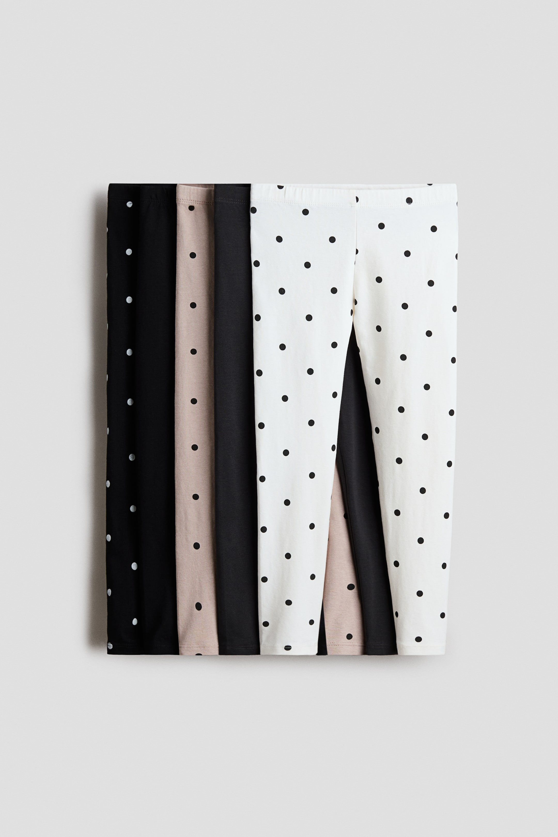 View larger image: "Legging yang diperbuat daripada jersi kapas lembut dengan pinggang bergetah kini dipamerkan dalam beberapa pasang yang dilipat. Rekaan yang kelihatan termasuk hitam solid, beige solid, hitam dengan titik polka putih, dan putih dengan titik polka hitam."