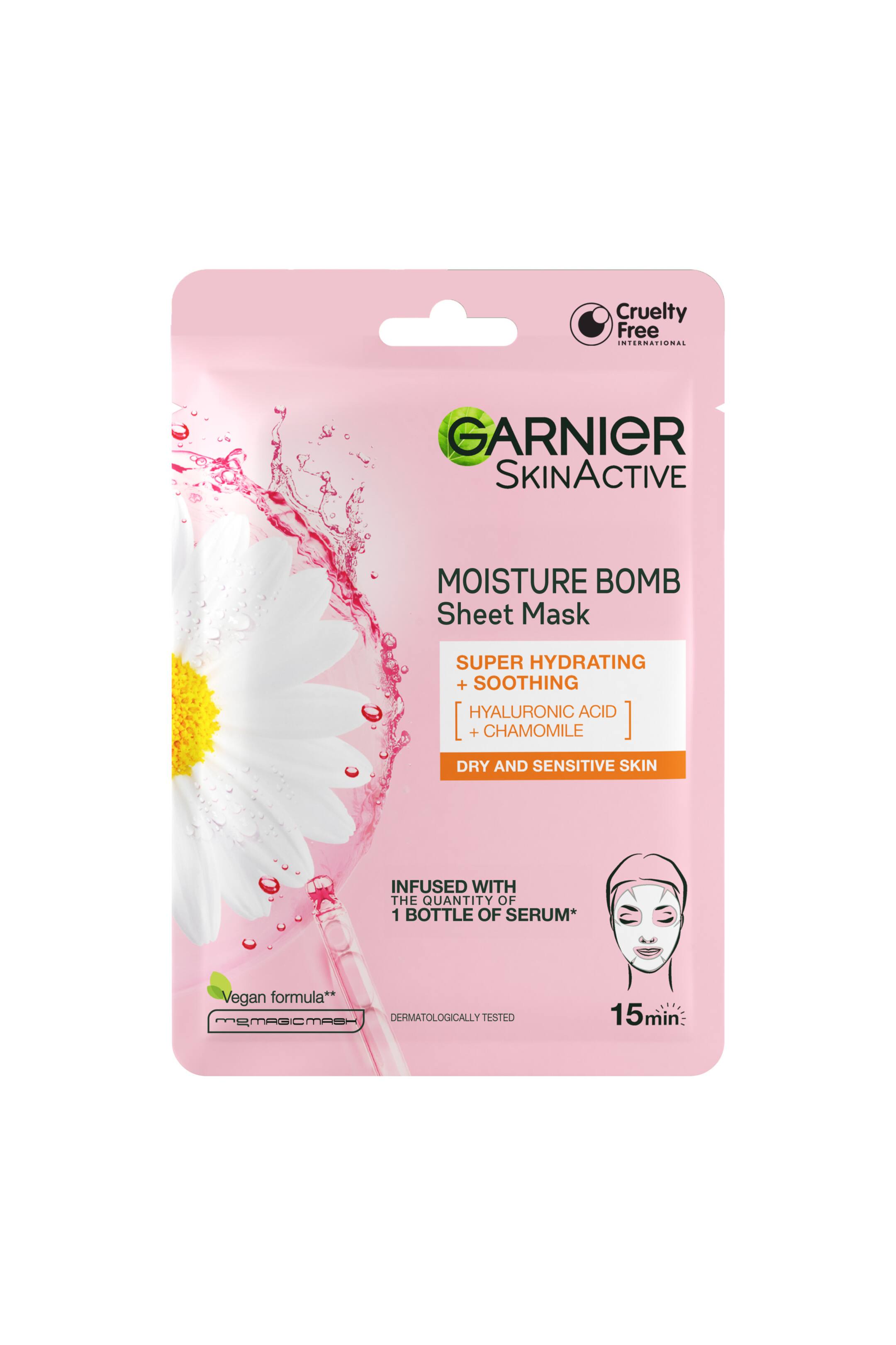 Se større billede: En lyserød Garnier SkinActive Moisture Bomb Sheet Mask-pose vender fremad. Forsiden af emballagen har en stor hvid marguerit, der er sprøjtet med lyserød væske, en klar glas-serumpipette og tekst, der fremhæver dens "Super Hydrating + Soothing"-formel med hyaluronsyre og kamille. En enkel stregtegning nederst til højre viser et ansigt med en sheet mask ved siden af en "15 min"-etiket.