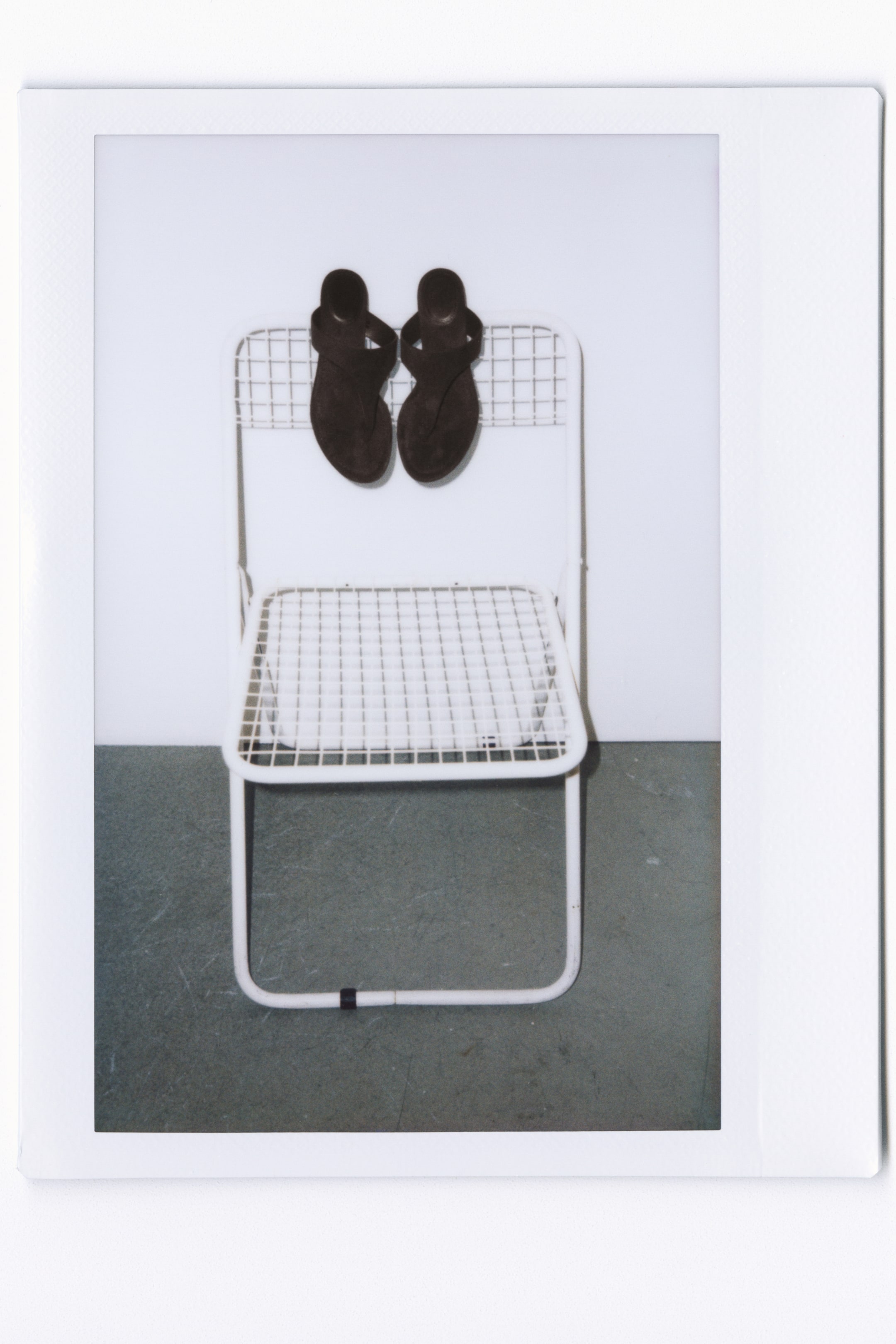 View larger image: Sandals featuring a soft, napped finish, oblique toes, a narrow foot strap and toe post, and partially covered kitten heels are placed on the back of a white wire-frame chair.