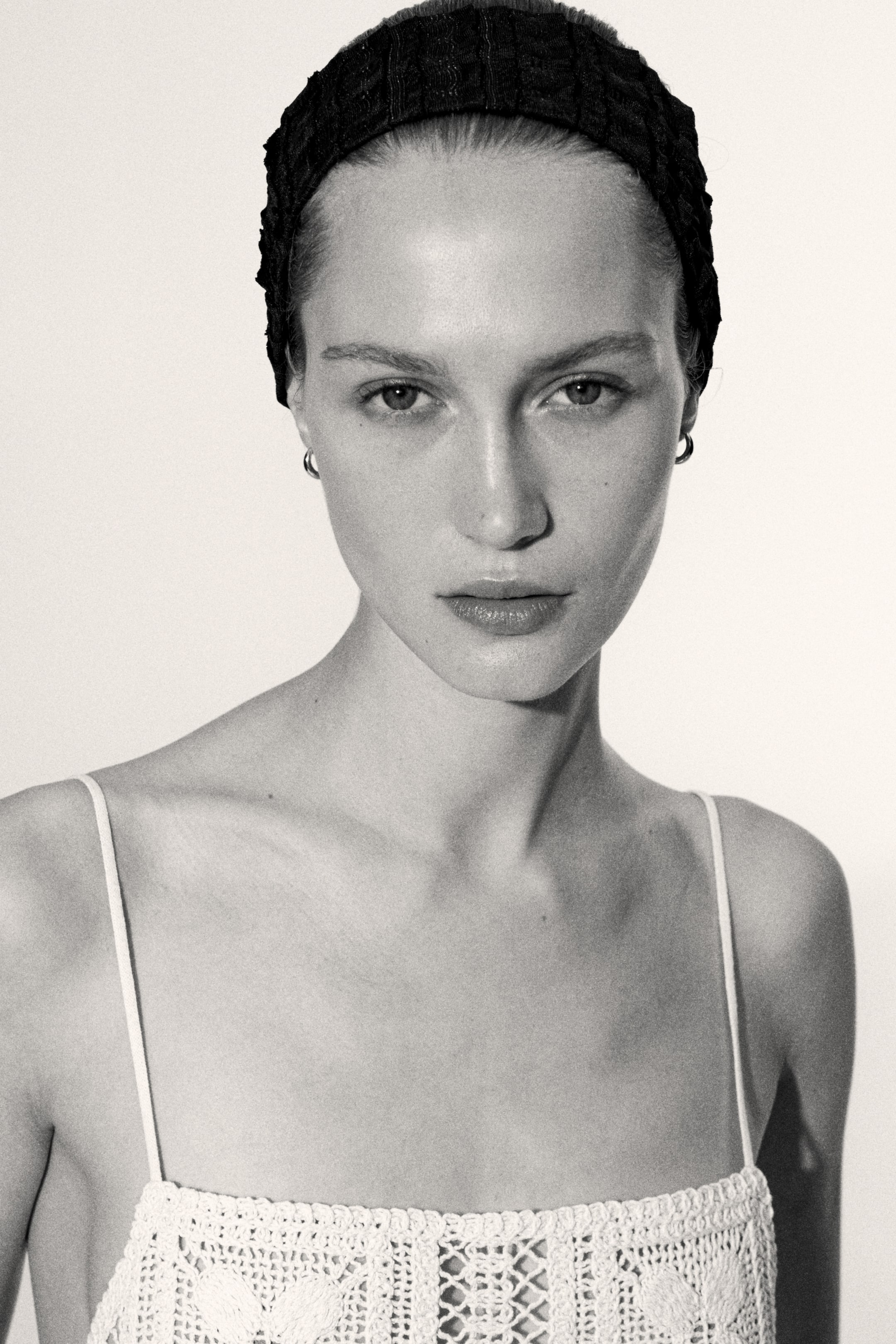 View larger image: A black headband with a gathered texture is being worn, paired with a white crocheted top showcasing thin spaghetti straps and a detailed openwork pattern featuring visible motifs across the bust.