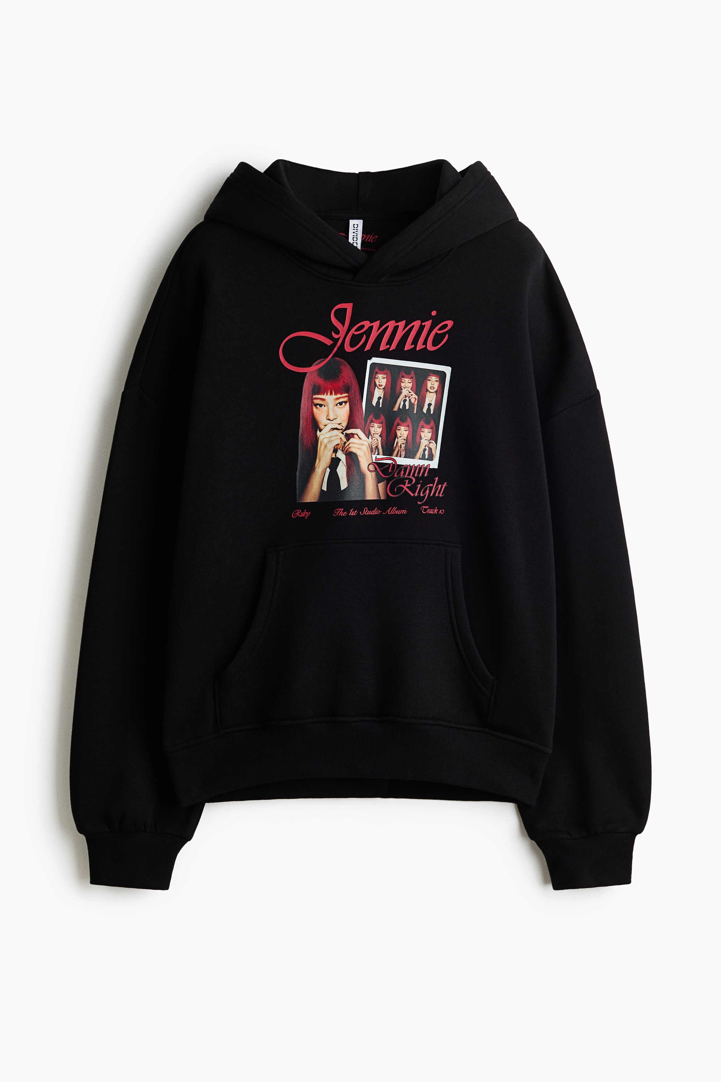 Một chiếc hoodie đen oversized với họa tiết in graphic ở mặt trước, túi kangaroo và vai trễ đang được người mẫu mặc. Chiếc hoodie được phối layer bên ngoài một áo tay dài sọc đỏ và đen, kết hợp cùng chân váy đen xếp ly.