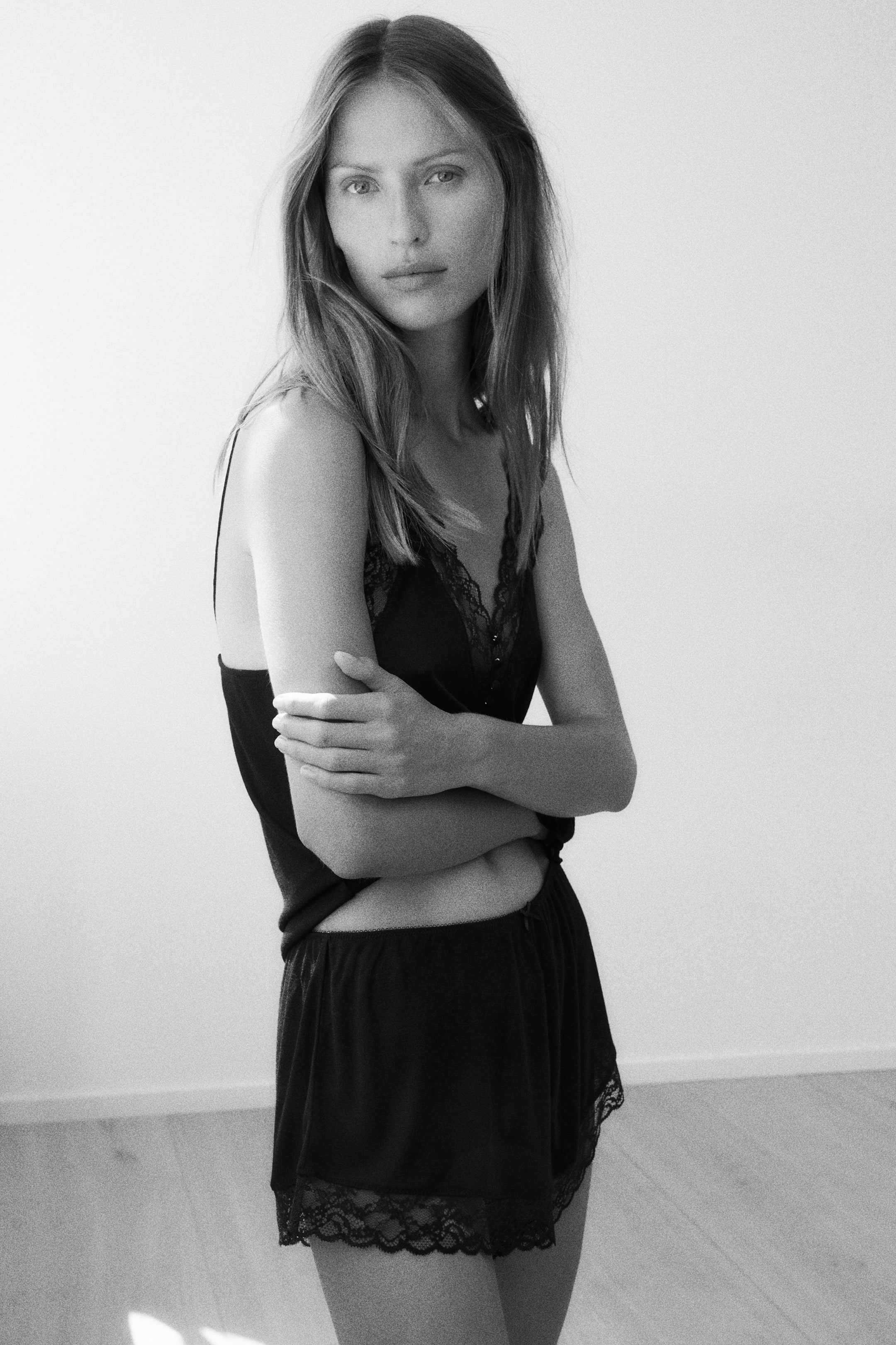 Voir une image plus grande: Un ensemble de camisole et short noir est porté, légèrement incliné vers la droite. La camisole présente de fines bretelles spaghetti et un décolleté en V orné d'une bordure en dentelle noire, tandis que le short assorti est doté d'une taille élastique et d'une bordure en dentelle noire festonnée le long de l'ourlet.