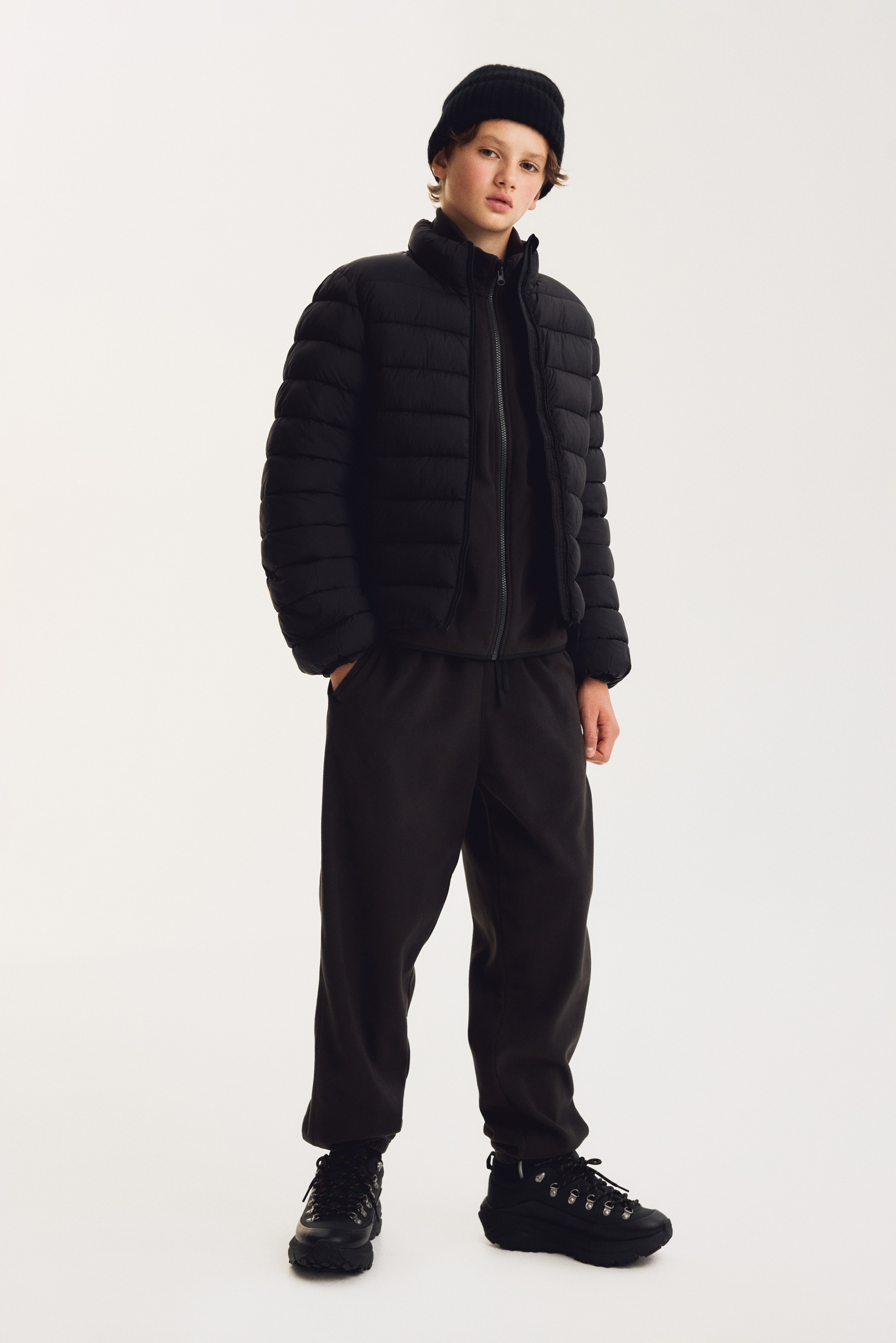 Dark brown fleece sweatpants are shown from the front, featuring a relaxed-fit design with an elasticated waistband, an adjustable matching drawstring, and elasticated cuffs at the hems.