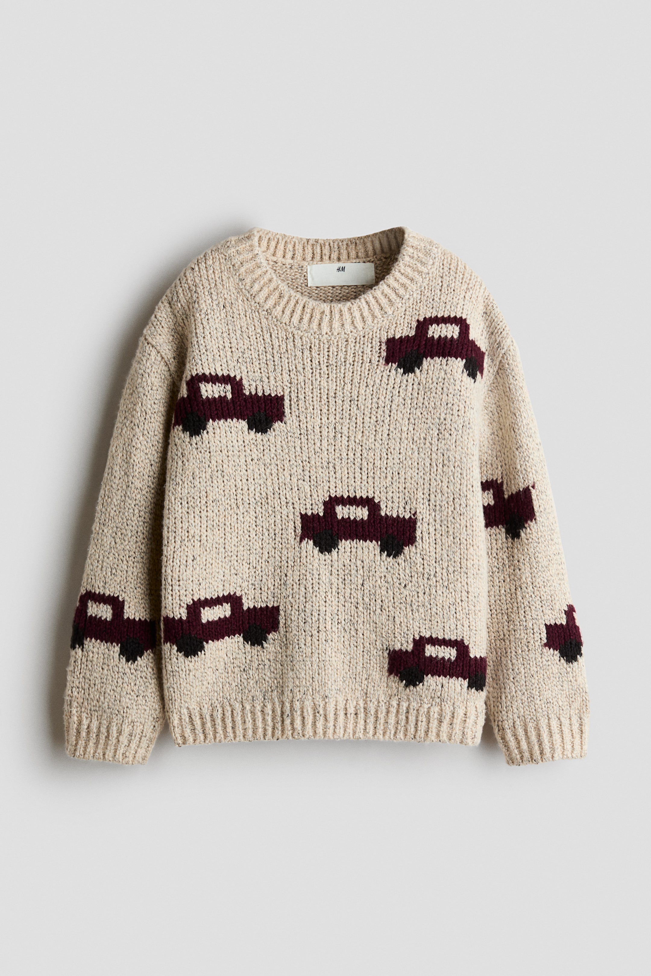 Visa större bild: En beige jacquardstickad tröja, visad framifrån, med ett mönster av mörkröda och svarta bilgrafiker. Tröjan har en rund ribbad halsringning, sänkta axlar samt ribbade muddar och fåll.