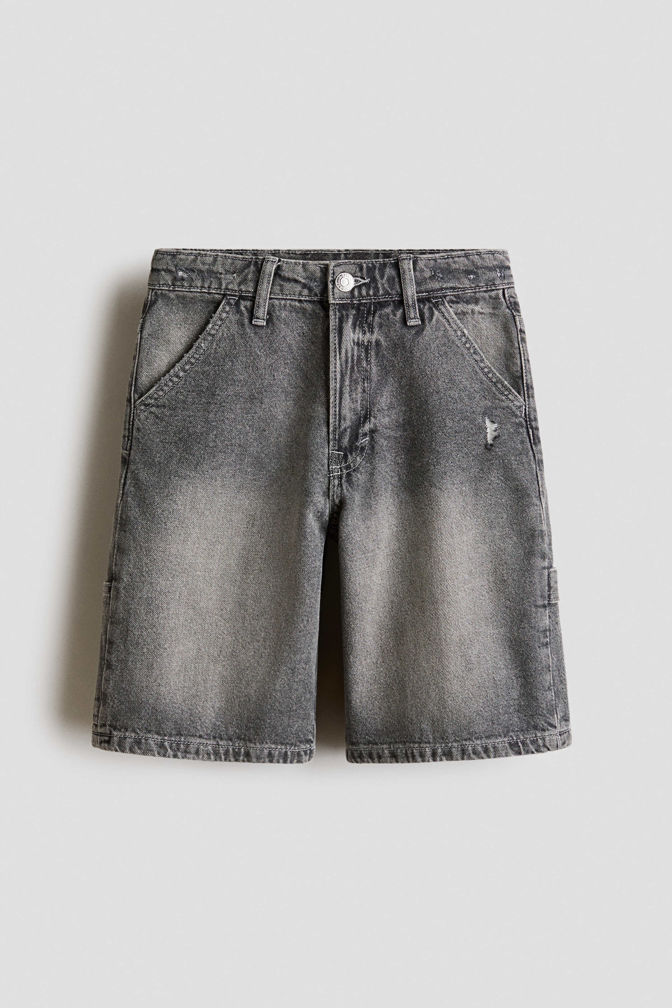 View larger image: These knee-length shorts in faded dark grey denim showcase a relaxed fit and are displayed from the front. They are crafted with a zip fly and button closure, diagonal front pockets, a hammer loop on the left side, and a small distressed detail near the right front pocket.