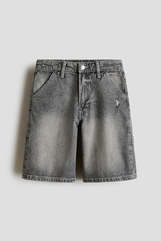 These knee-length shorts in faded dark grey denim feature a loose fit and are displayed from the front. They are designed with a zip fly and button fastening, diagonal front pockets, a hammer loop on the left side, and a small distressed detail near the right front pocket. - 1