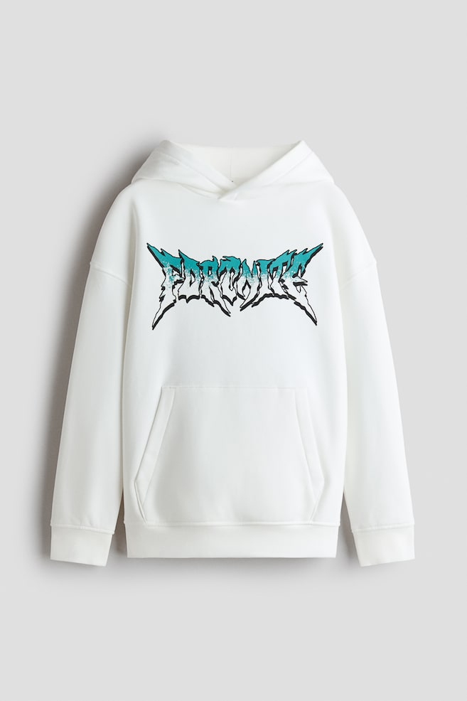A front-facing view of a loose-fit white hoodie featuring a wrap-front lined hood, dropped shoulders, and a kangaroo pocket. The chest is displaying a stylized, jagged "FORTNITE" graphic printed in a teal and white gradient with a black outline. - 1