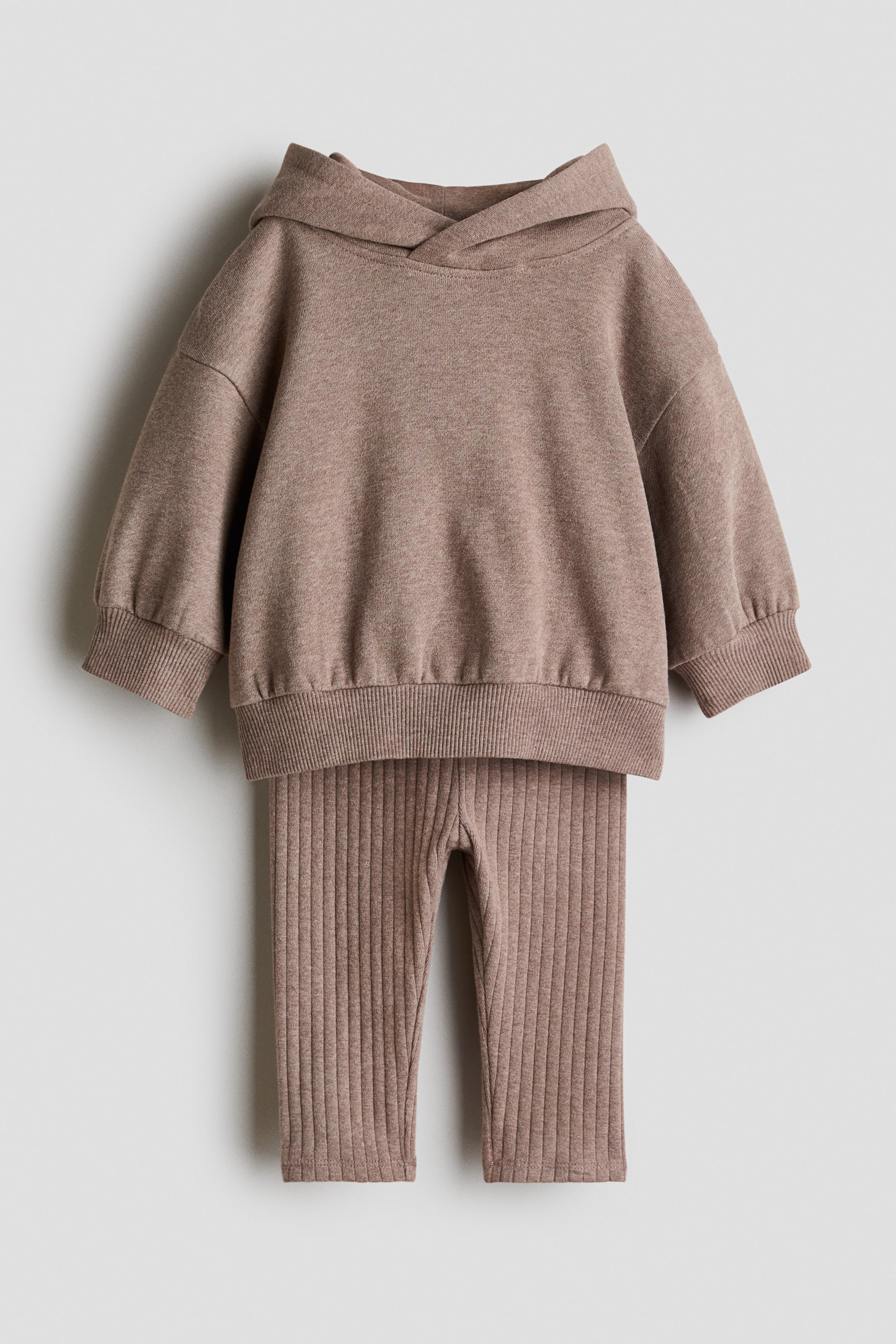 Agrandir l'image: Un ensemble deux pièces marron clair, comprenant un sweat à capuche et un legging côtelé assorti, est présenté de face. Le sweat à capuche est doté d'une capuche doublée avec un devant croisé, des épaules tombantes, des manches longues, et des poignets et ourlet côtelés, tandis que le legging présente un motif côtelé vertical.