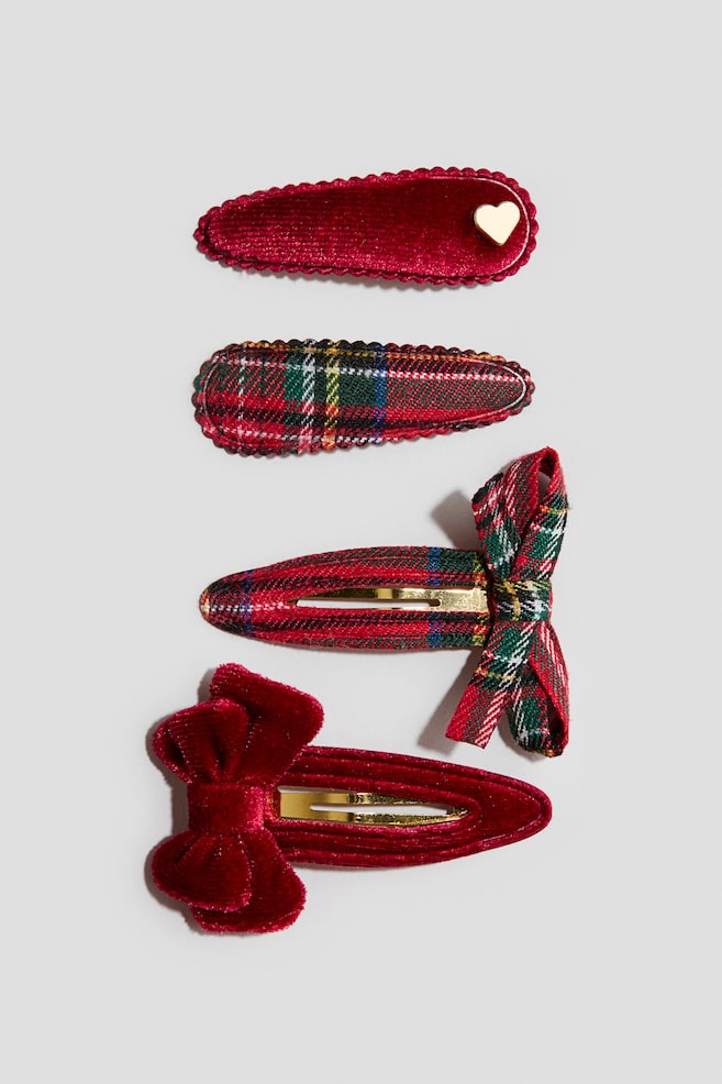 A set of four hair clips is displaying a mix of red velvet and red-and-green plaid designs. The top two clips are featuring scalloped edges, with one showcasing a small gold heart detail, while the bottom two are presenting matching velvet and plaid bows alongside gold-toned metal centers. - 1