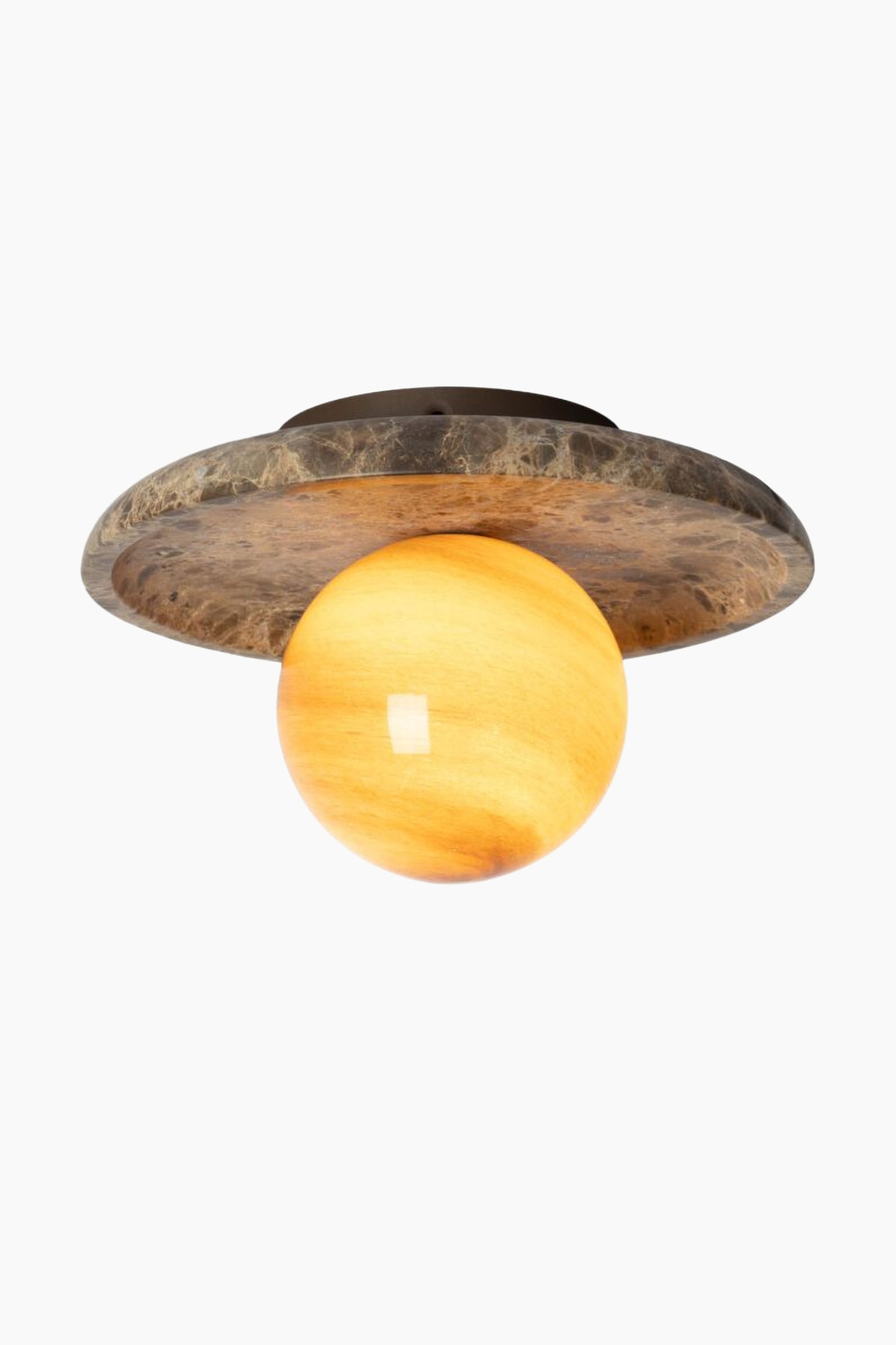 Een opbouwarmatuur toont een gloeiende, bolvormige kap met warme gele en oranje aders. De verlichte bol steekt uit vanuit het midden van een brede, holle, cirkelvormige plafondkap, vervaardigd uit bruin gemarmerde steen. - 1