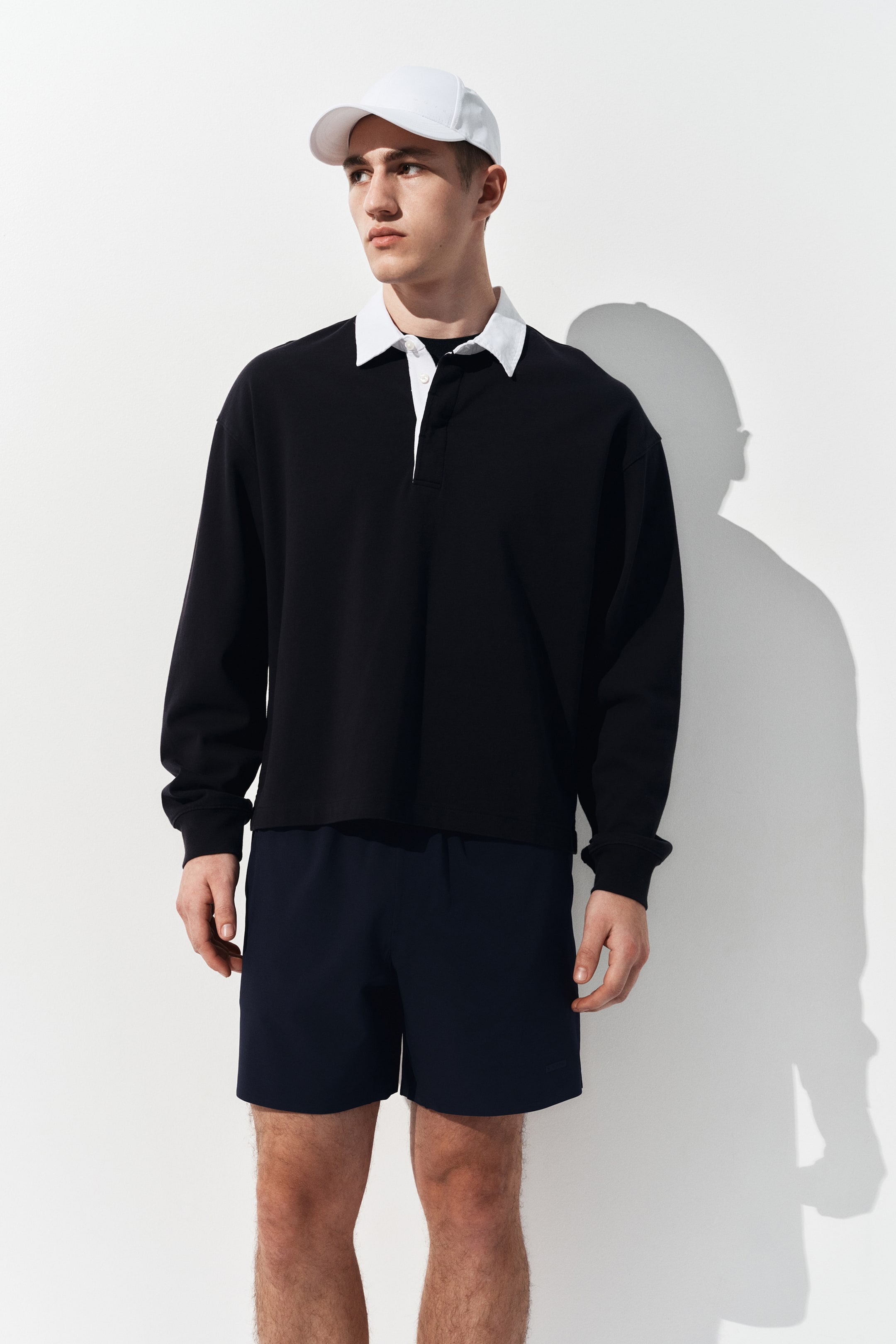 View larger image: A black long-sleeved rugby shirt with a relaxed fit, featuring a white pointed collar and a white three-button placket, showcased from the front.