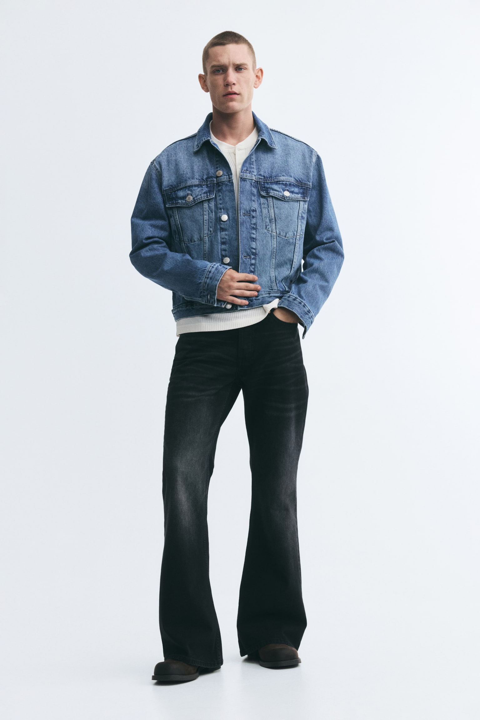 A light blue denim jacket is shown from the front, featuring a classic point collar, a button-up front fastening with silver-toned metal buttons, and two buttoned chest flap pockets. The jacket has two vertical welt side pockets, long sleeves with buttoned cuffs, and a lightly washed finish. - 1