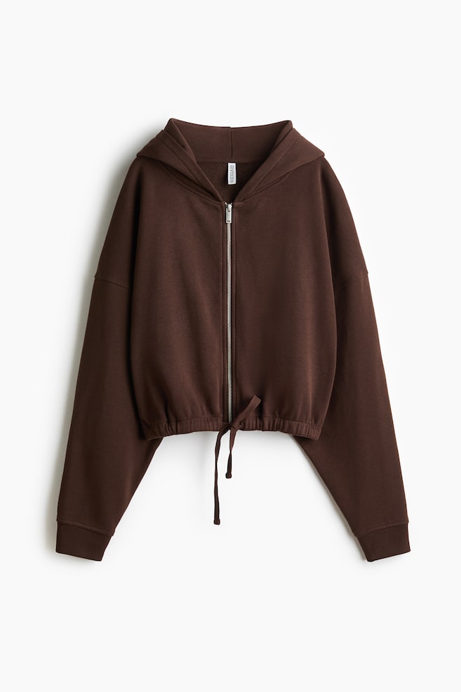A brown hooded jacket is presenting its front view, featuring a full-length silver zipper. It is showcasing an elasticated hem with a visible drawstring tie at the front, and long sleeves with ribbed cuffs. - 1