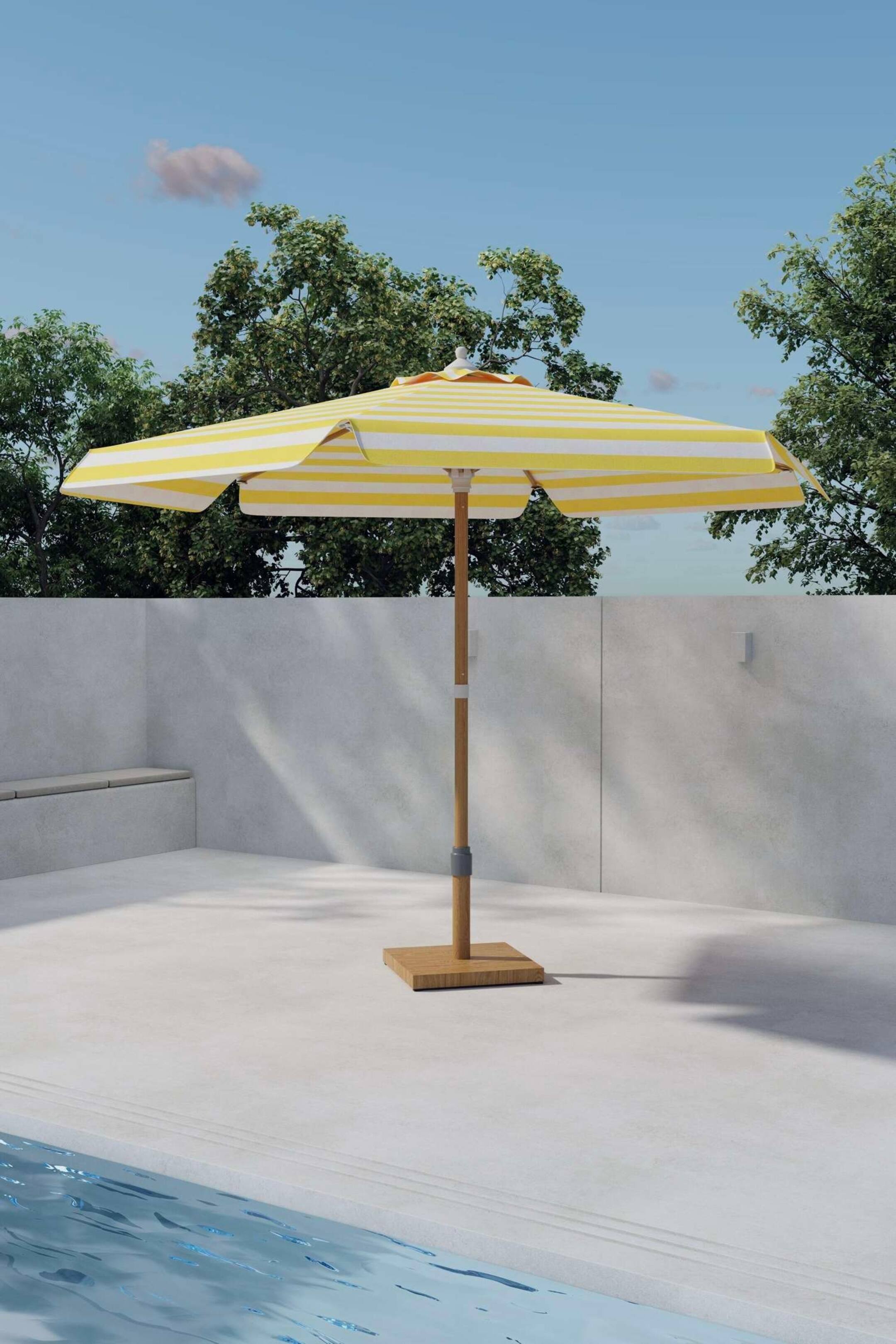 Agrandir l'image: Un parasol de terrasse se tient droit, mettant en valeur une toile rayée jaune et blanche avec des bords festonnés. Son mât en bois clair s'étend à partir d'une base carrée en bois, avec un mécanisme de réglage gris visible sur le mât.