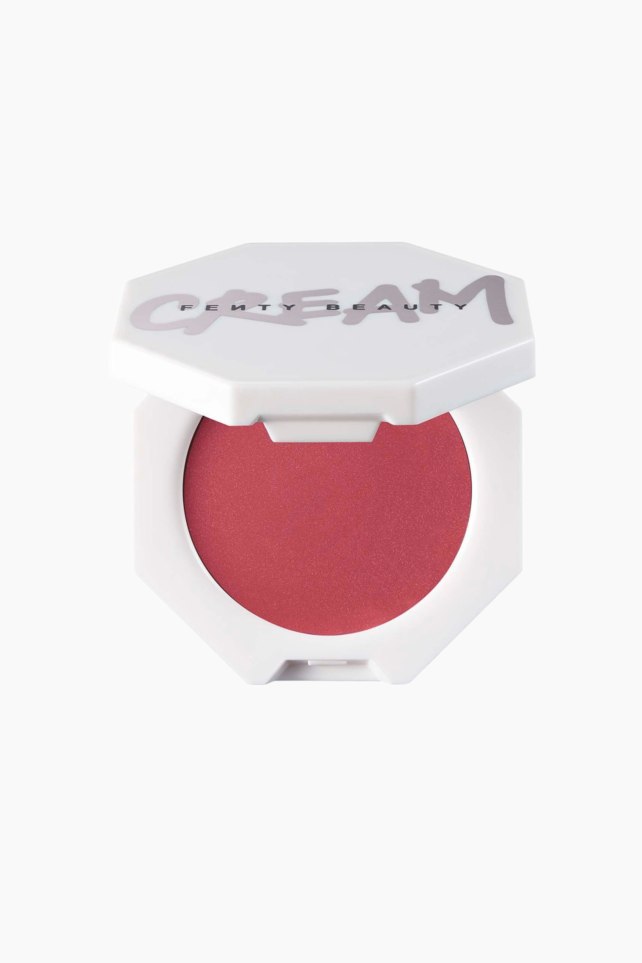 Näytä suurempi kuva: Cheeks Out Freestyle Cream Blush on valkoisessa, kahdeksankulmaisessa kompaktissa, etupuoli kameraan päin ja kansi hieman raollaan, jolloin näkyviin tulee syvän ruusunpunaisen kermapunan pyöreä sävyastia. Kannessa lukee tyylitellyllä vaaleanvioletilla tekstillä ”CREAM”, ja keskelle on painettu ”FENTY BEAUTY”.