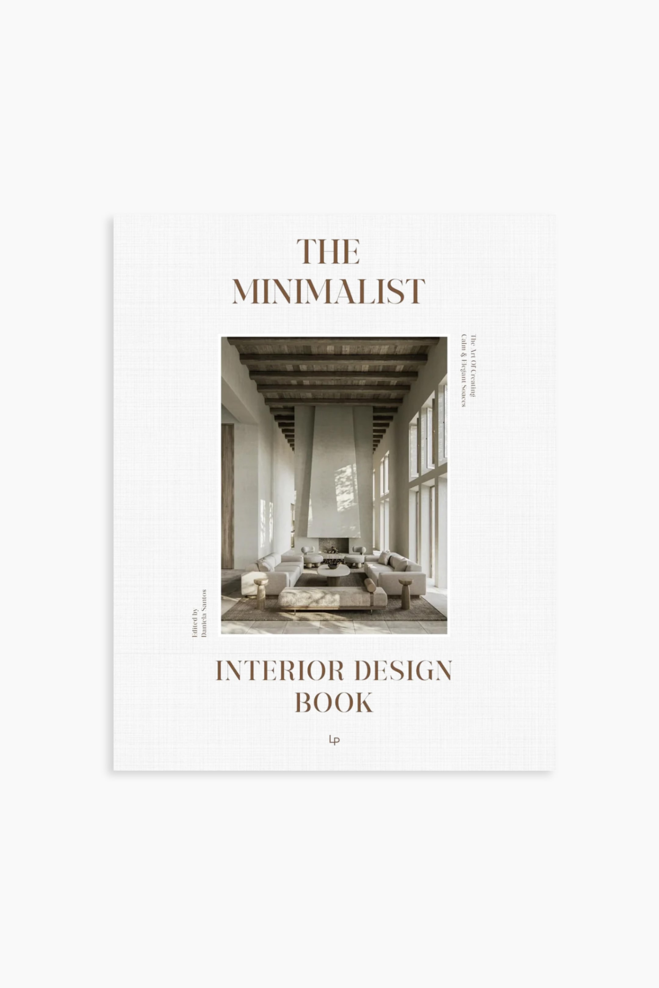 Visa större bild: En bok visar upp sitt texturerade ljusa off-white framsida, med den bruna titeln 'THE MINIMALIST INTERIOR DESIGN BOOK' placerad ovanför och under en central bild. Denna bild avbildar ett minimalistiskt vardagsrumsinteriör, medan ytterligare text lyder 'Konsten att skapa lugna & eleganta utrymmen' och 'Redigerad av Daniela Santos'.