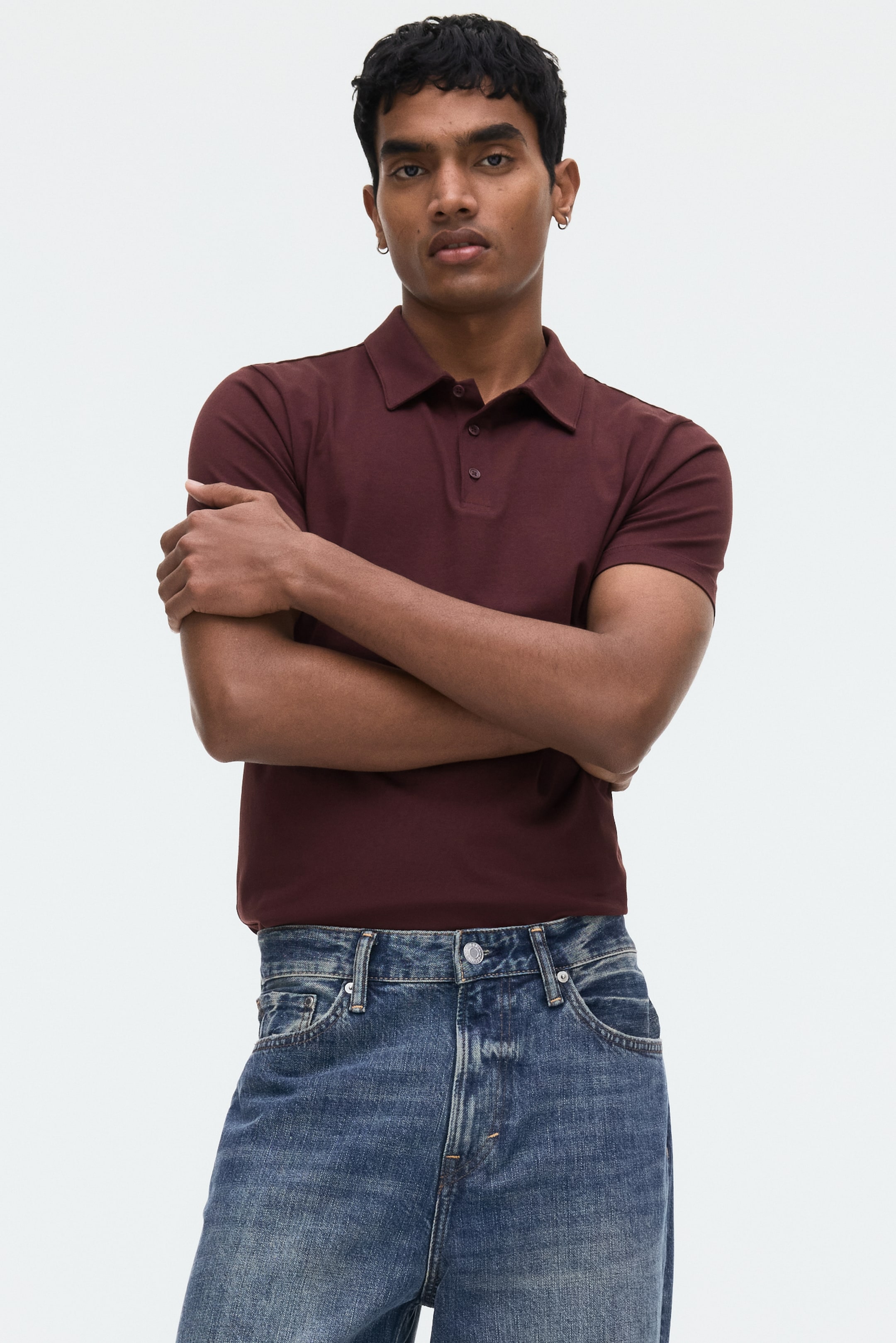 View larger image: The deep maroon polo shirt is positioned facing forward, showcasing a traditional collar and a two-button placket. It is crafted with short sleeves, highlighting a tailored silhouette.