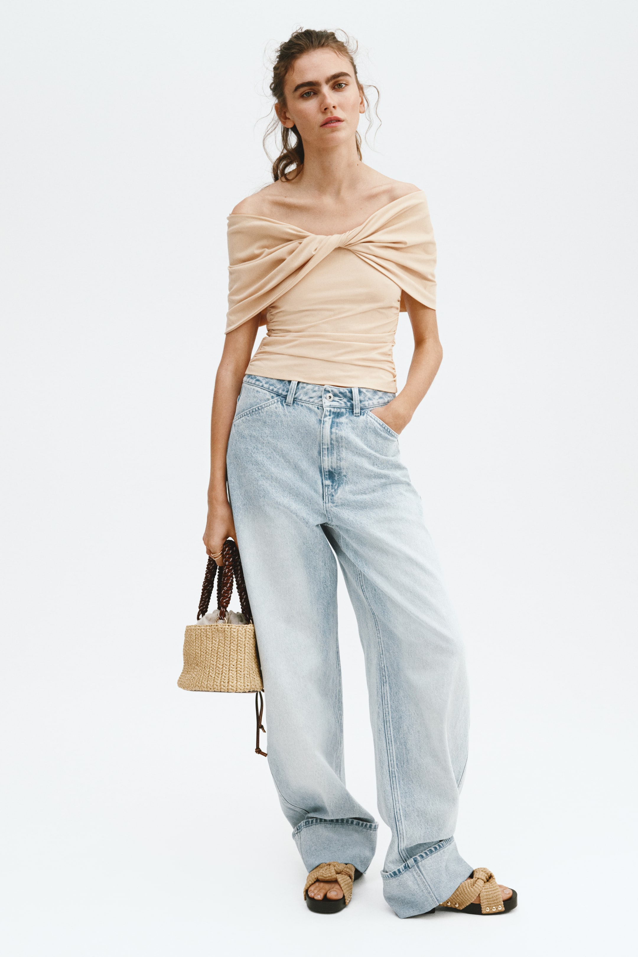 View larger image: Light blue wide-leg jeans feature a faded wash, a high-waisted design with angled front pockets, and wide, rolled cuffs, with the long hem pooling at the ankles.