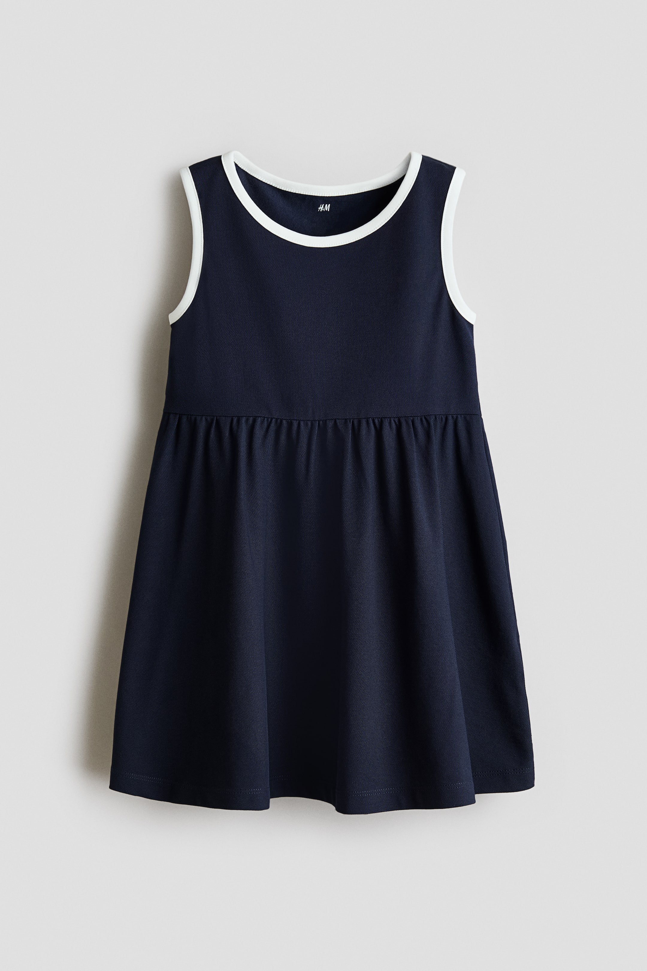 View larger image: Navy biru sleeveless dress ini mempersembahkan pandangan hadapan, dengan leher bulat dan lubang lengan yang dihiasi trim putih. Jahitan berlipat menonjolkan garis pinggang, dan skirt kembang memanjang daripadanya.