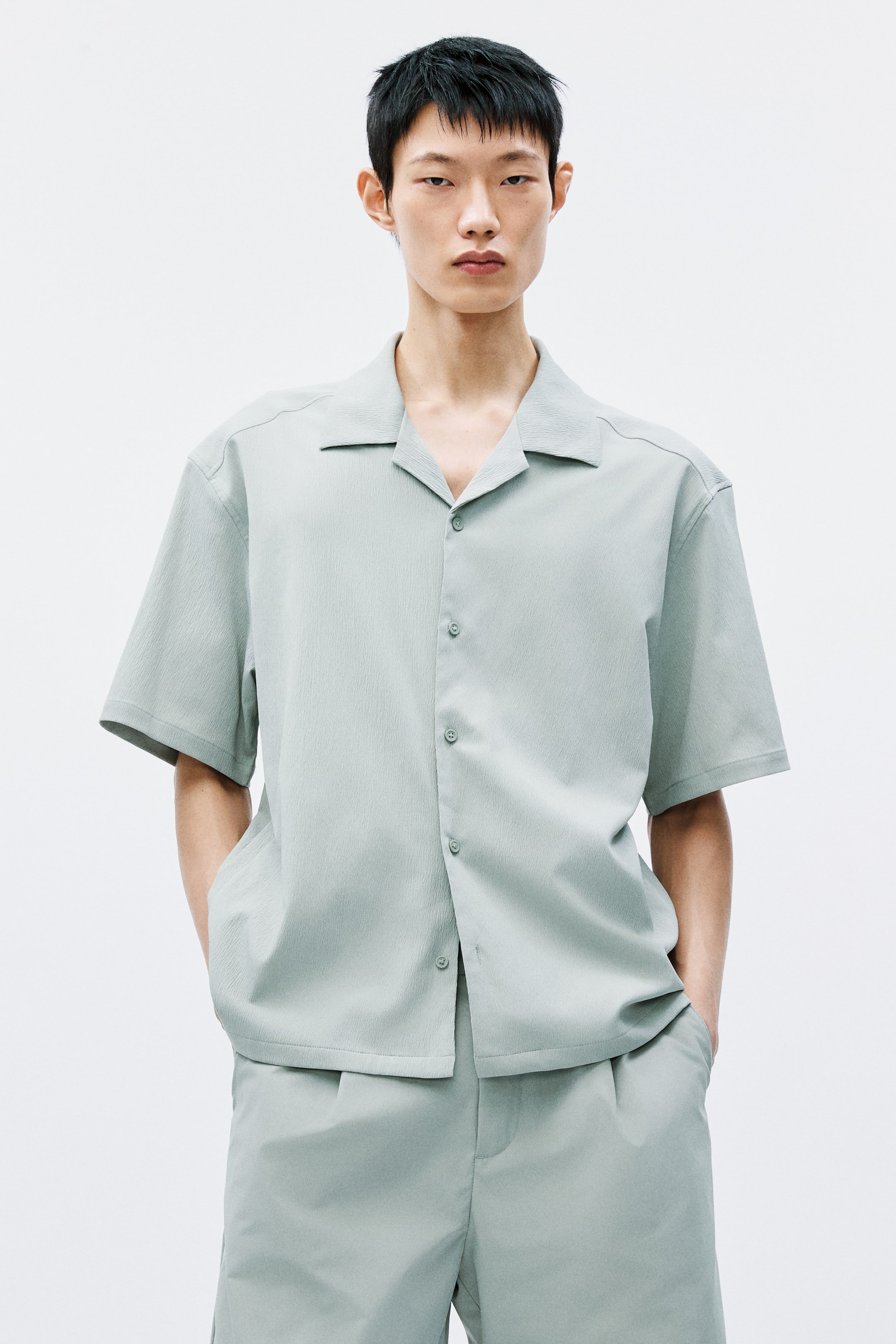 View larger image: A light green short-sleeved shirt showcasing a textured fabric, complete with a Cuban collar and a button-front adorned with matching buttons. Displayed front-facing, it is paired with coordinating light green shorts that exhibit a relaxed fit and feature side pockets.