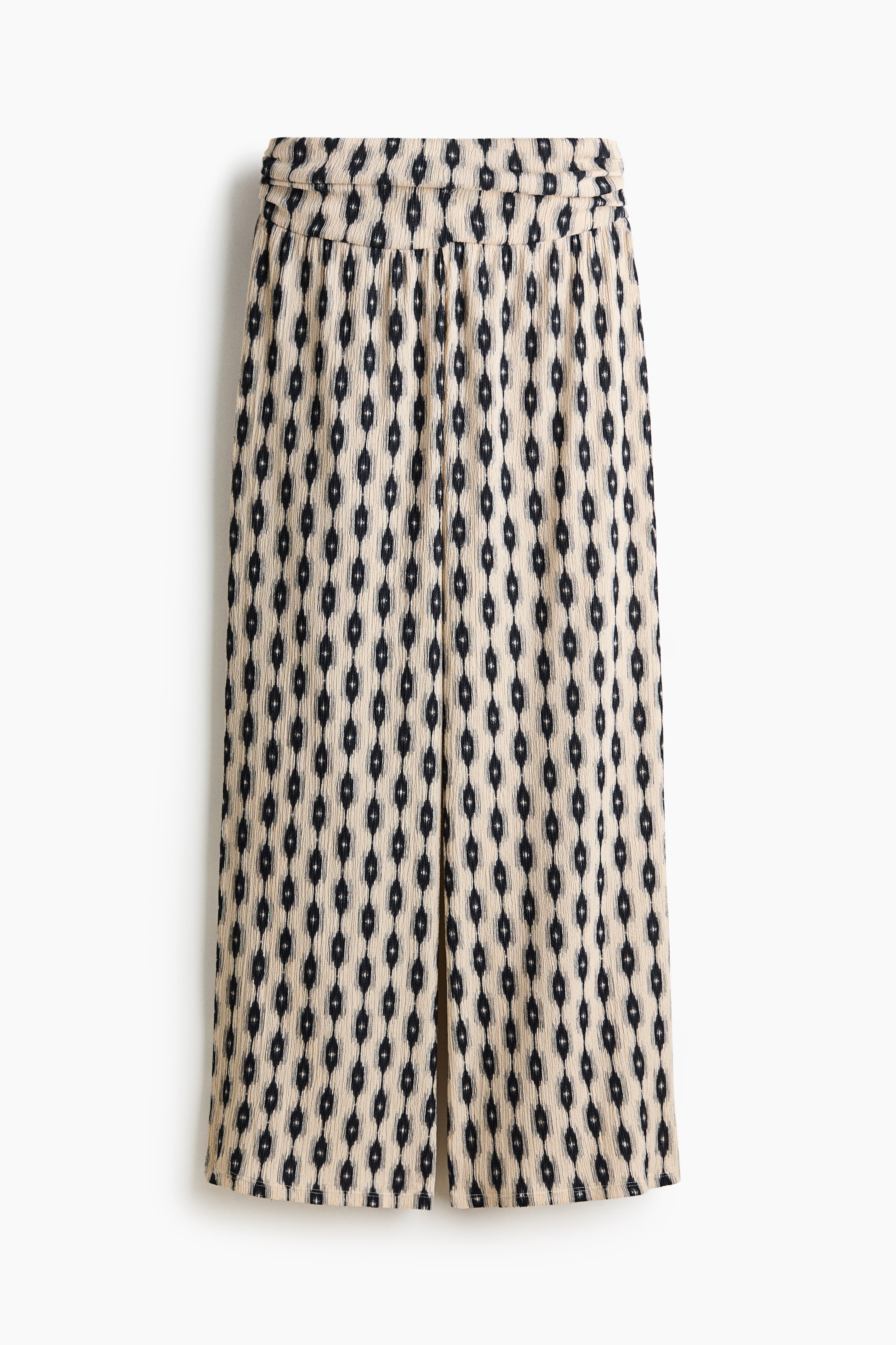 View larger image: The culottes are displayed from the front, highlighting a beige, vertically textured fabric adorned with a repeating black ikat design. The waistband appears gathered, and the wide legs feature a subtle central crease running down the front.