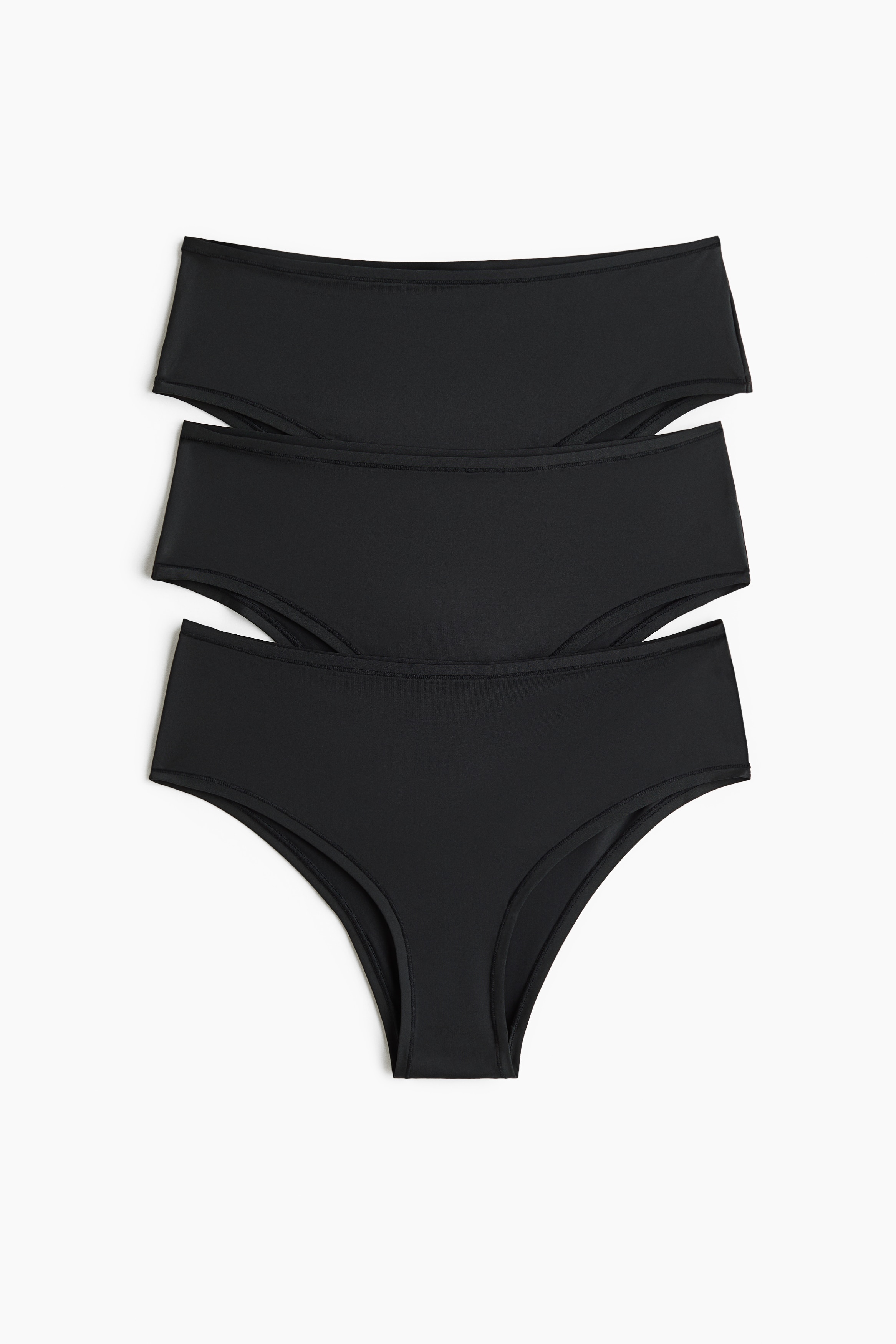 Een zwarte gewatteerde beha en bijpassende zwarte slip worden vanuit een zijaanzicht gepresenteerd. De beha heeft gladde, voorgevormde cups en een transparant mesh paneel aan de zijkant, en de slip heeft een gladde, elastische tailleband.