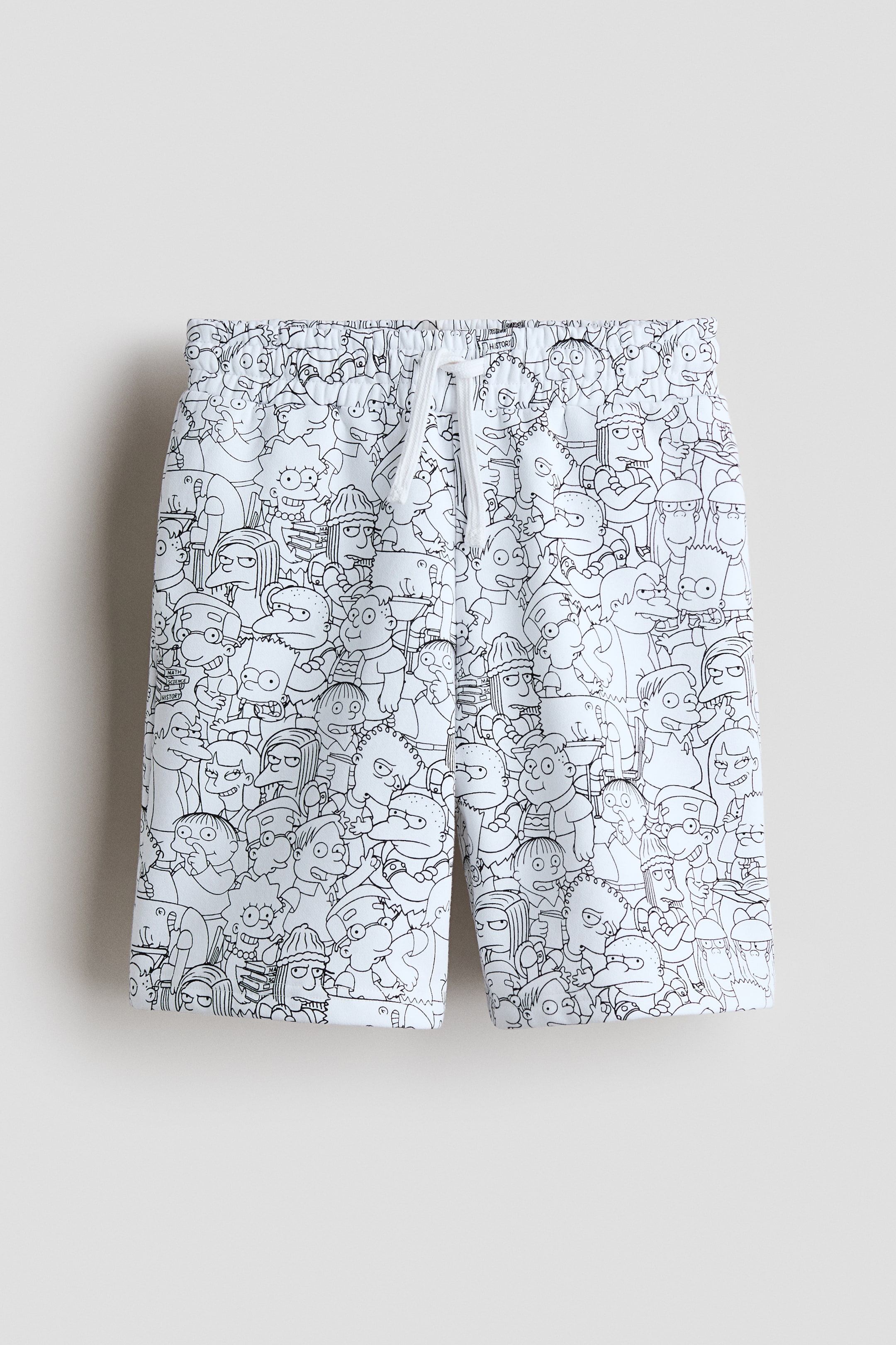 View larger image: A pair of shorts is facing forward, showcasing an all-over black outline print of various cartoon characters on white fabric. A white drawstring, tied in a bow, is visible at the elastic waistband.
