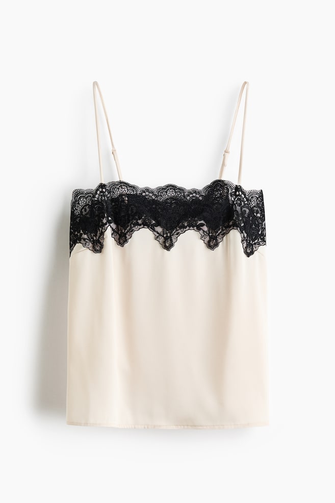 A light beige camisole showcases a black lace trim with a scalloped edge along its neckline. It features thin, adjustable shoulder straps and a smooth fabric body, presented from the front. - 1
