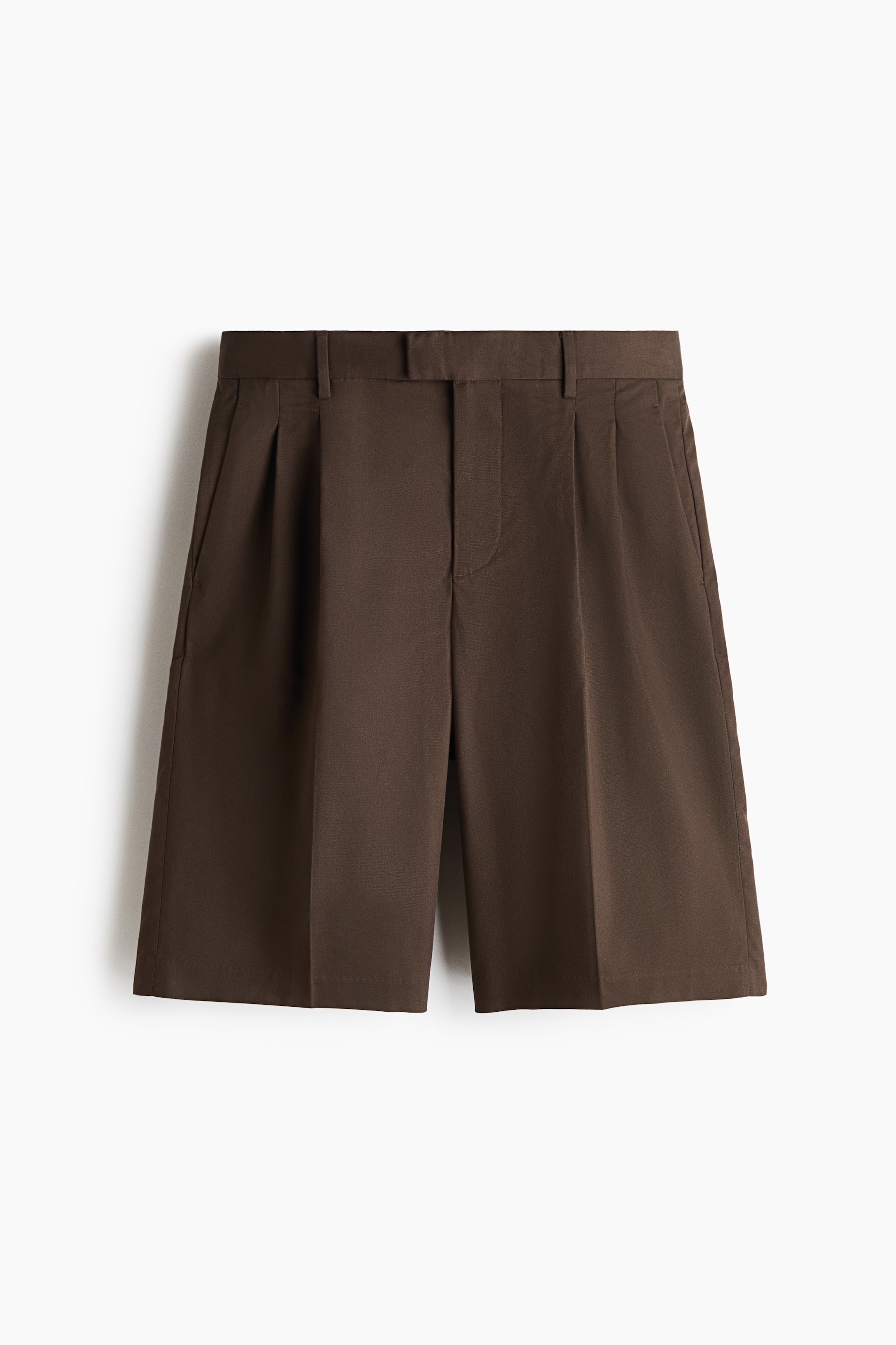 View larger image: The dark brown shorts are shown from the front, featuring a flat waistband with belt loops and a concealed front closure. Double pleats extend down each leg from the waistband, with slanted side pockets visible at the hips, and the shorts are tailored in a wide-leg, knee-length fit with a straight hem.