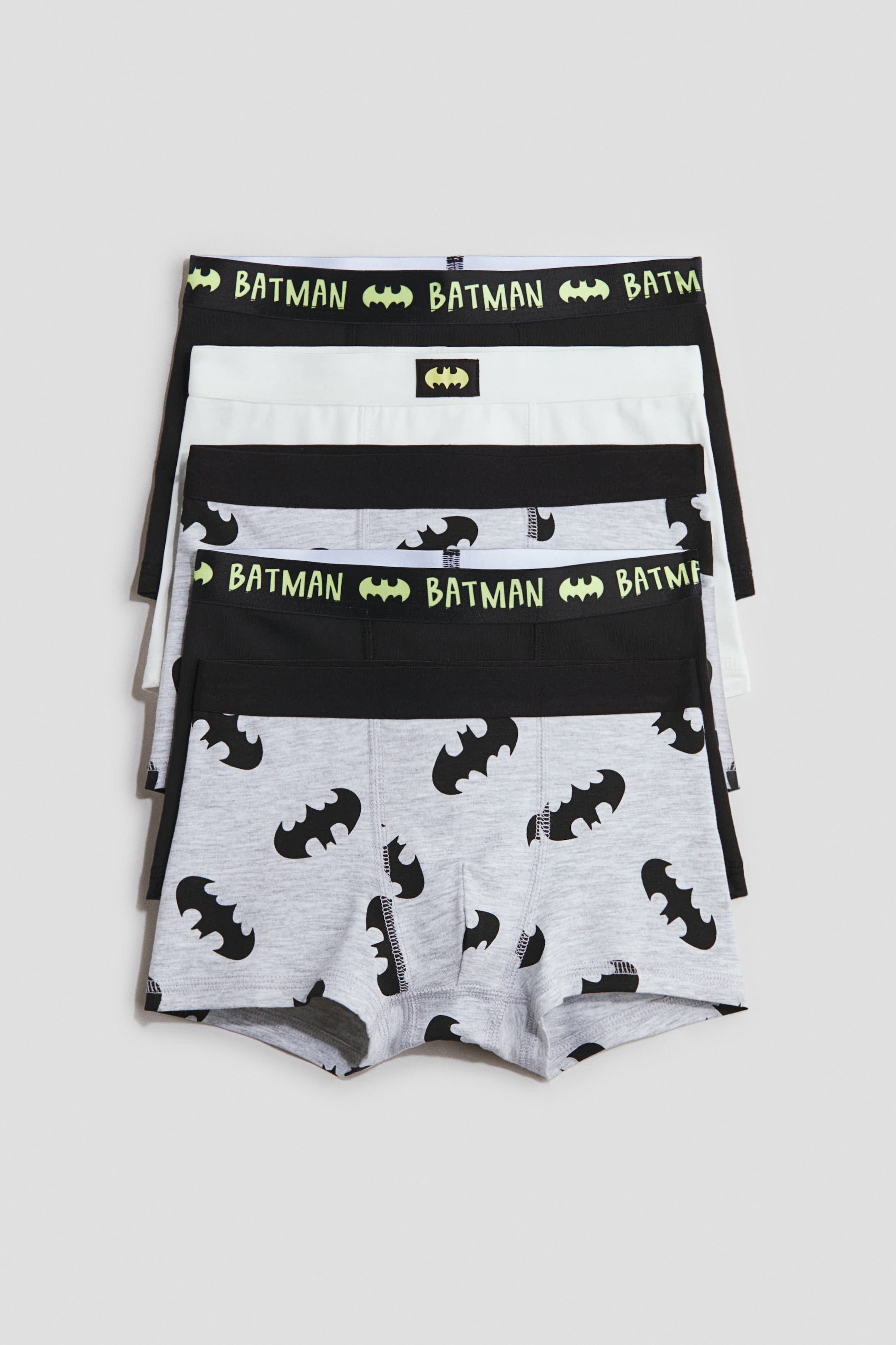 Vis større bilde: Boksertruser i trykt bomullsjersey er stablet, vendt fremover, med korte ben, elastiske midjer og foret front. De vises i fargene svart, hvit og gråmelert, med Batman-logo og teksttrykk på midjebåndene, og et heldekkende Batman-logo-trykk på det gråmelerte paret.