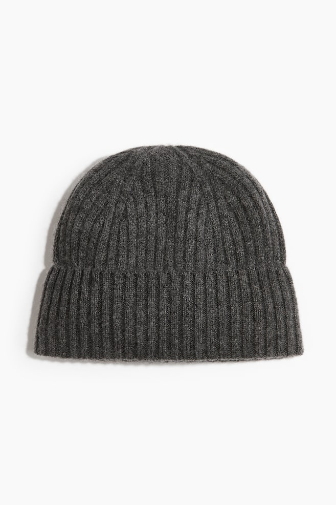 Un bonnet en cachemire gris foncé à maille côtelée est présenté de face, avec un large revers retroussé à lâourlet et une forme structurée en dôme, agrémentée de côtes verticales sur toute la surface. - 1
