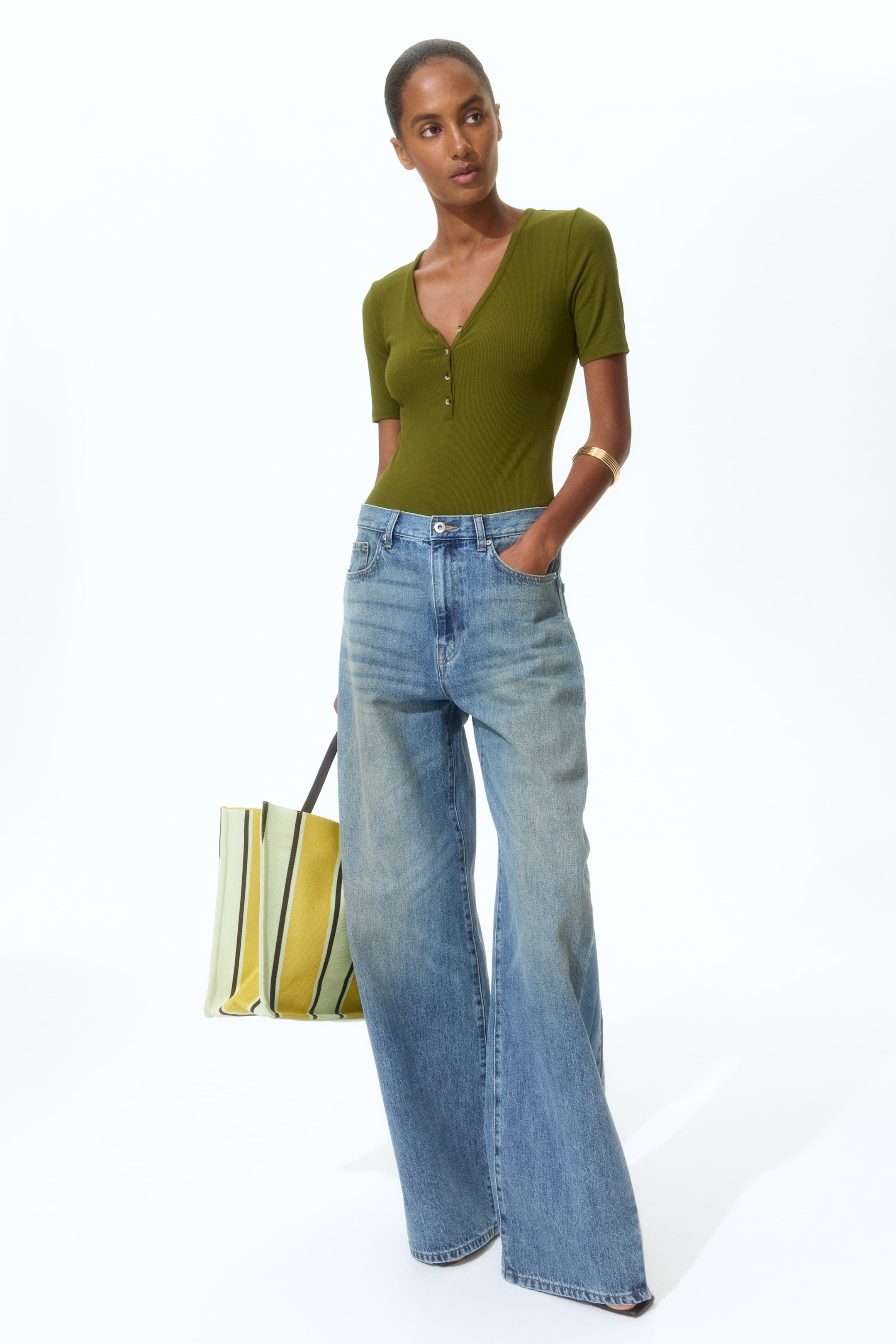 View larger image: The light blue denim jeans are displayed from the front, slightly angled towards the right, highlighting a high-waisted, wide-leg silhouette. They feature faded details, a button and zipper closure, and offer a relaxed fit through the legs, with the hem gathering at the ankles.