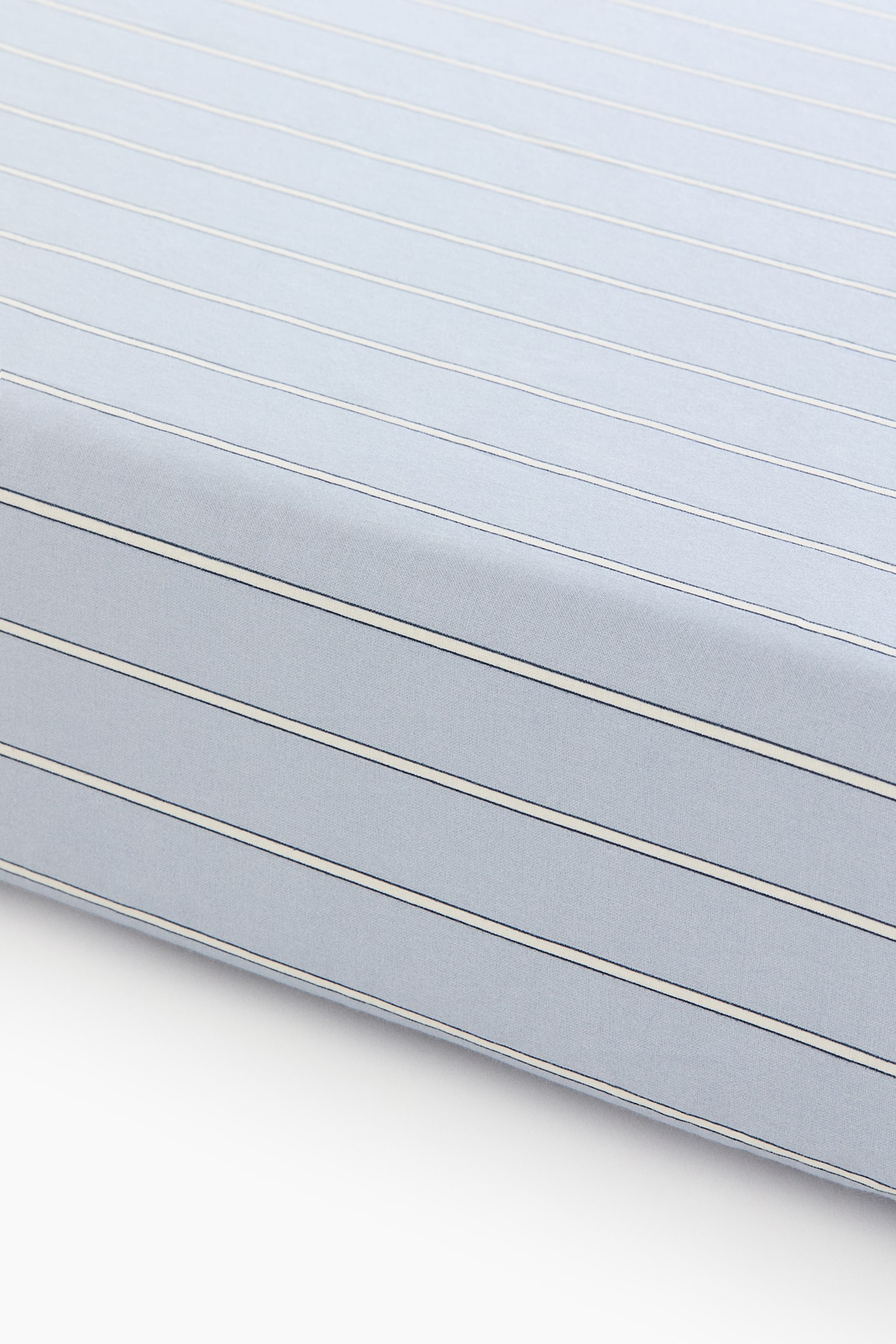 A light blue fabric showcases a striped pattern, featuring alternating thin dark blue lines and wider cream lines. The fabric presents a subtle texture and a gentle fold. - 1