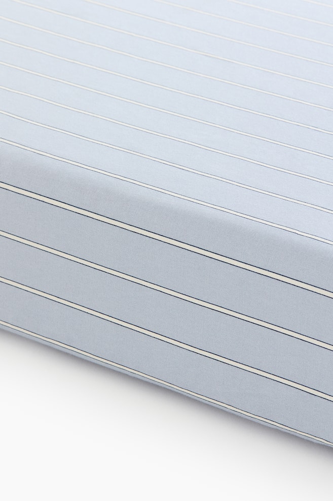 A light blue fabric showcases a striped pattern, featuring alternating thin dark blue lines and wider cream lines. The fabric presents a subtle texture and a gentle fold. - 1