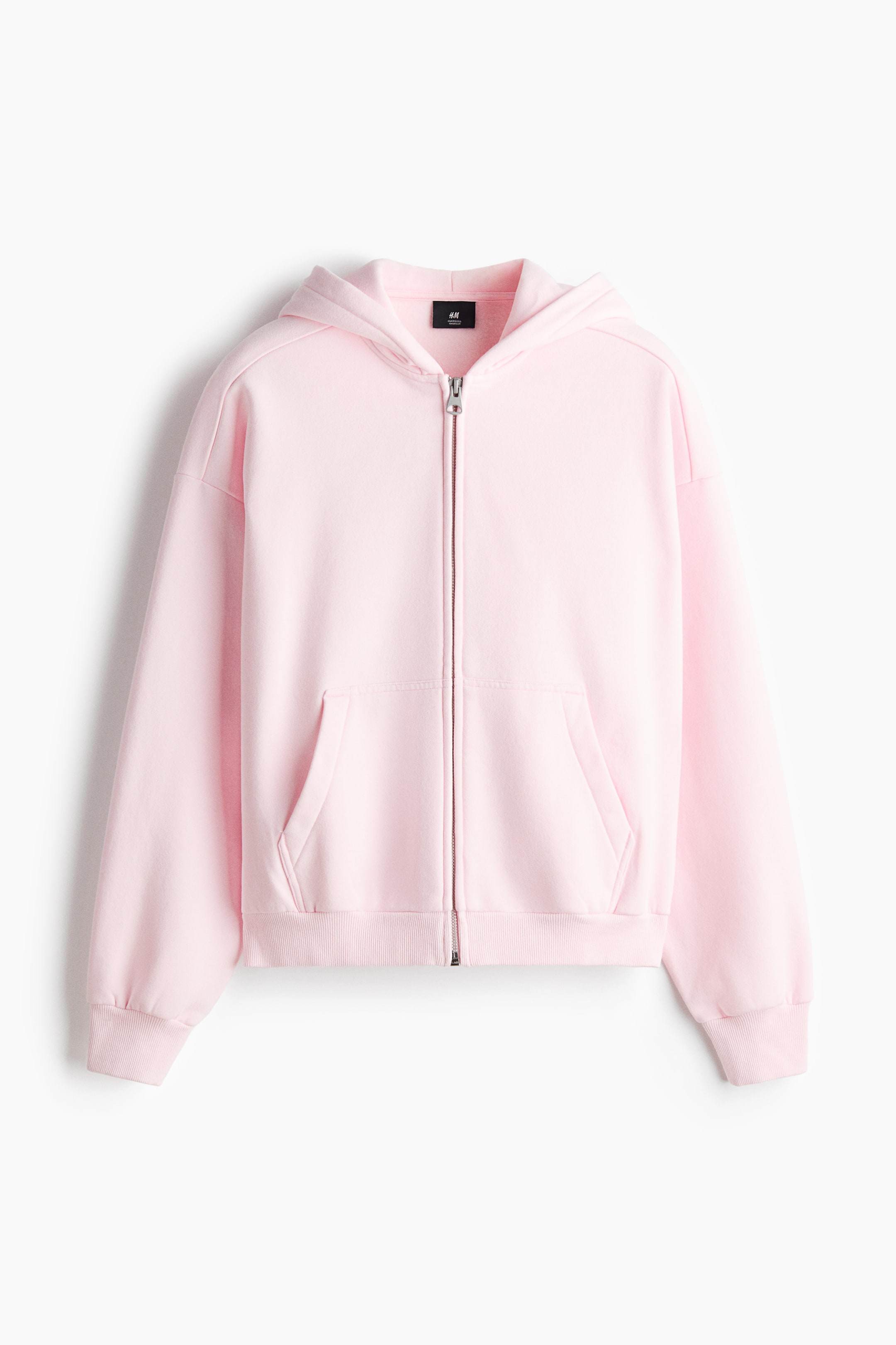 View larger image: A pink zip-through hoodie is presented facing front, featuring an oversized fit with dropped shoulders, long sleeves, and a jersey-lined hood. It is showing a concealed front zip, front pockets, and wide ribbed trims on the cuffs and hem.