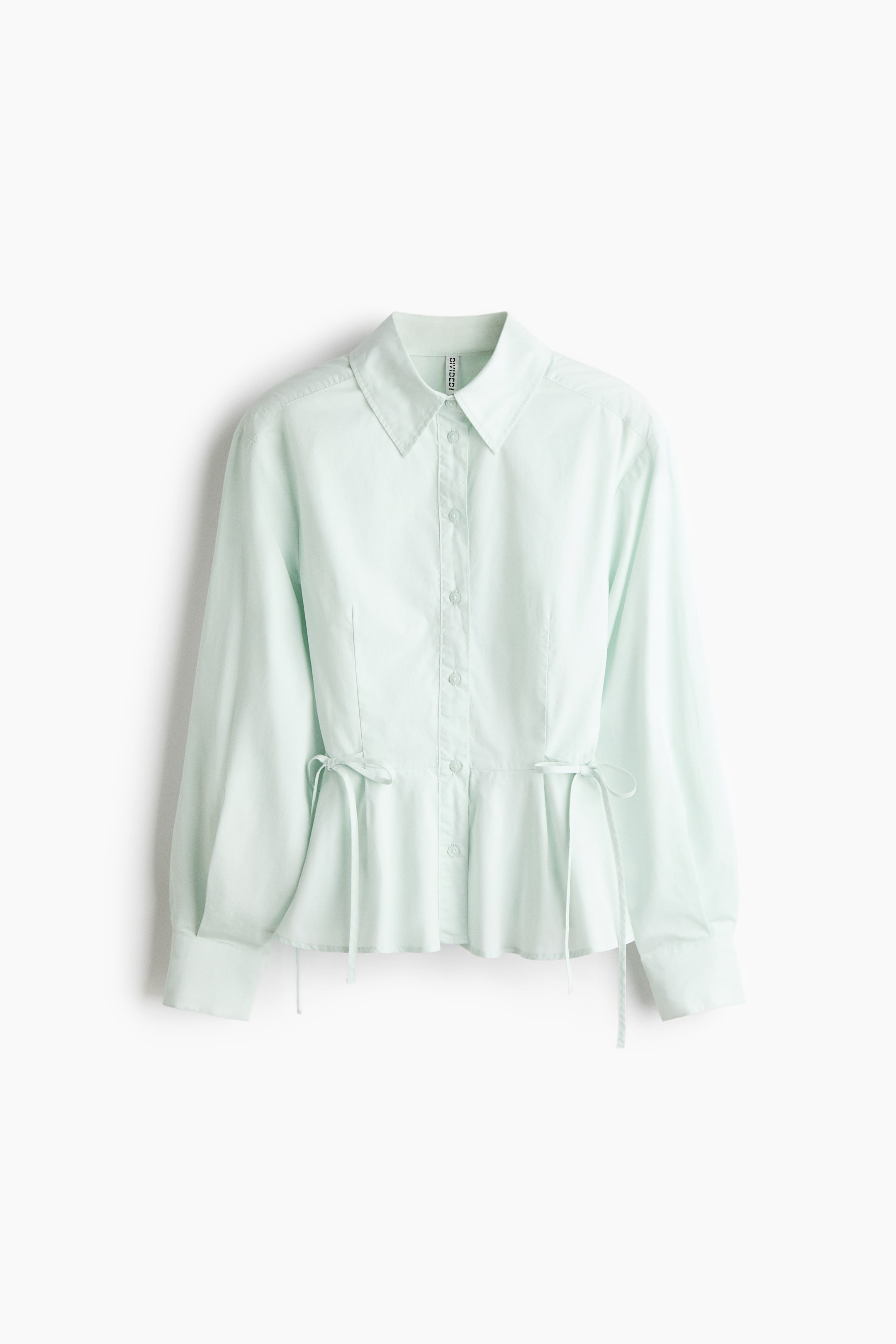 View larger image: A light mint green long-sleeved shirt is shown from the front, featuring a point collar, a button-down front, and a cinched waist with adjustable drawstring ties on each side. The shirt is designed with vertical seams on the bodice, long sleeves with wide cuffs, and a flared peplum hem.