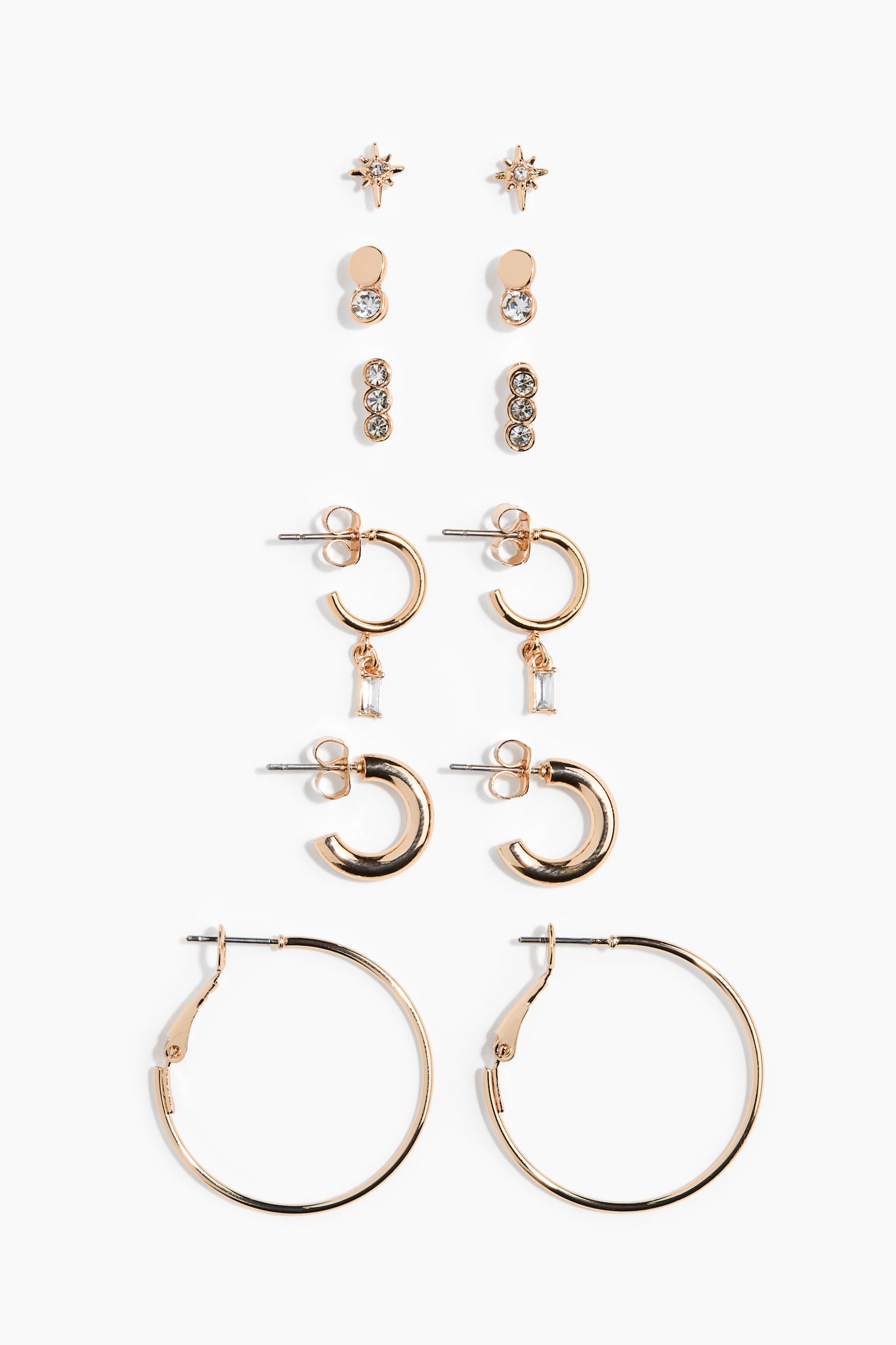 This rose gold-toned earring set, shown from the front, displays six distinct pairs of earrings arranged vertically. The collection features three pairs of studs, including starbursts, double-circle designs and triple-crystal bars, alongside three pairs of hoop earrings in varying sizes, including one pair with dangling rectangular baguette crystals.