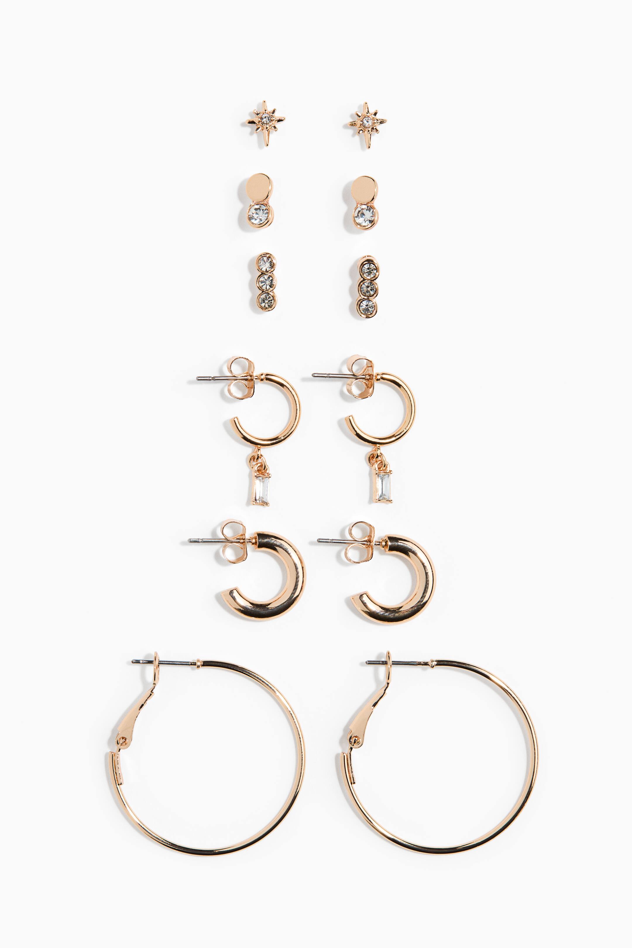 View larger image: This rose gold-toned earring set, shown from the front, features six distinct pairs of earrings arranged vertically. The collection includes three pairs of studs, including starburst, double-circle designs, and triple-crystal bars, along with three pairs of hoop earrings in varying sizes, including one pair with dangling rectangular baguette crystals.