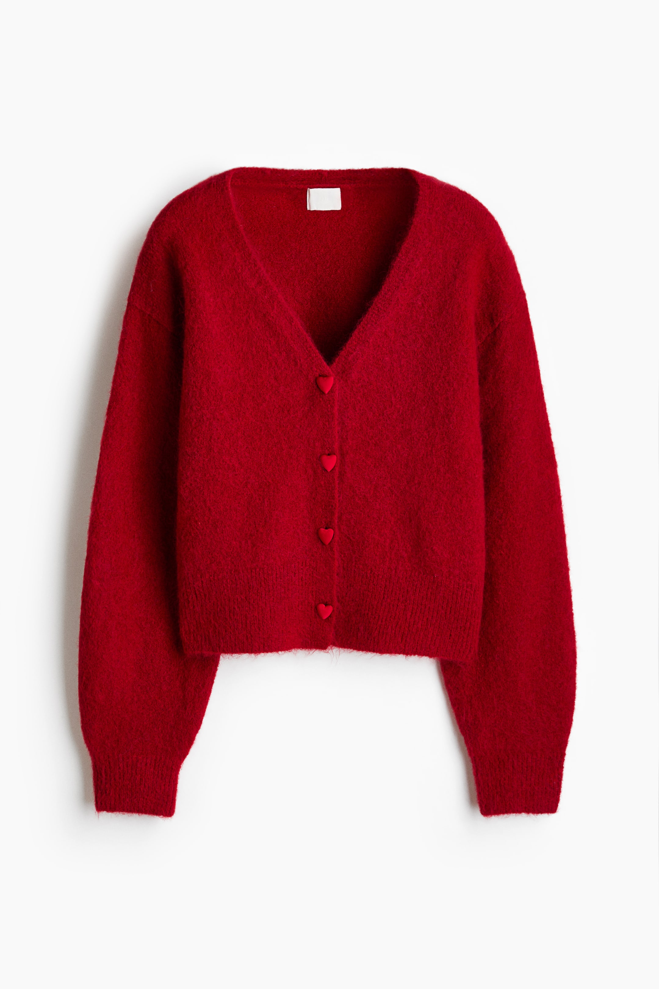 View larger image: A red knit cardigan is facing forward, featuring a deep V-neckline, long sleeves with ribbed cuffs, and a ribbed hem. The garment is showcasing a soft, fuzzy texture and is fastening down the front with four red, heart-shaped buttons.