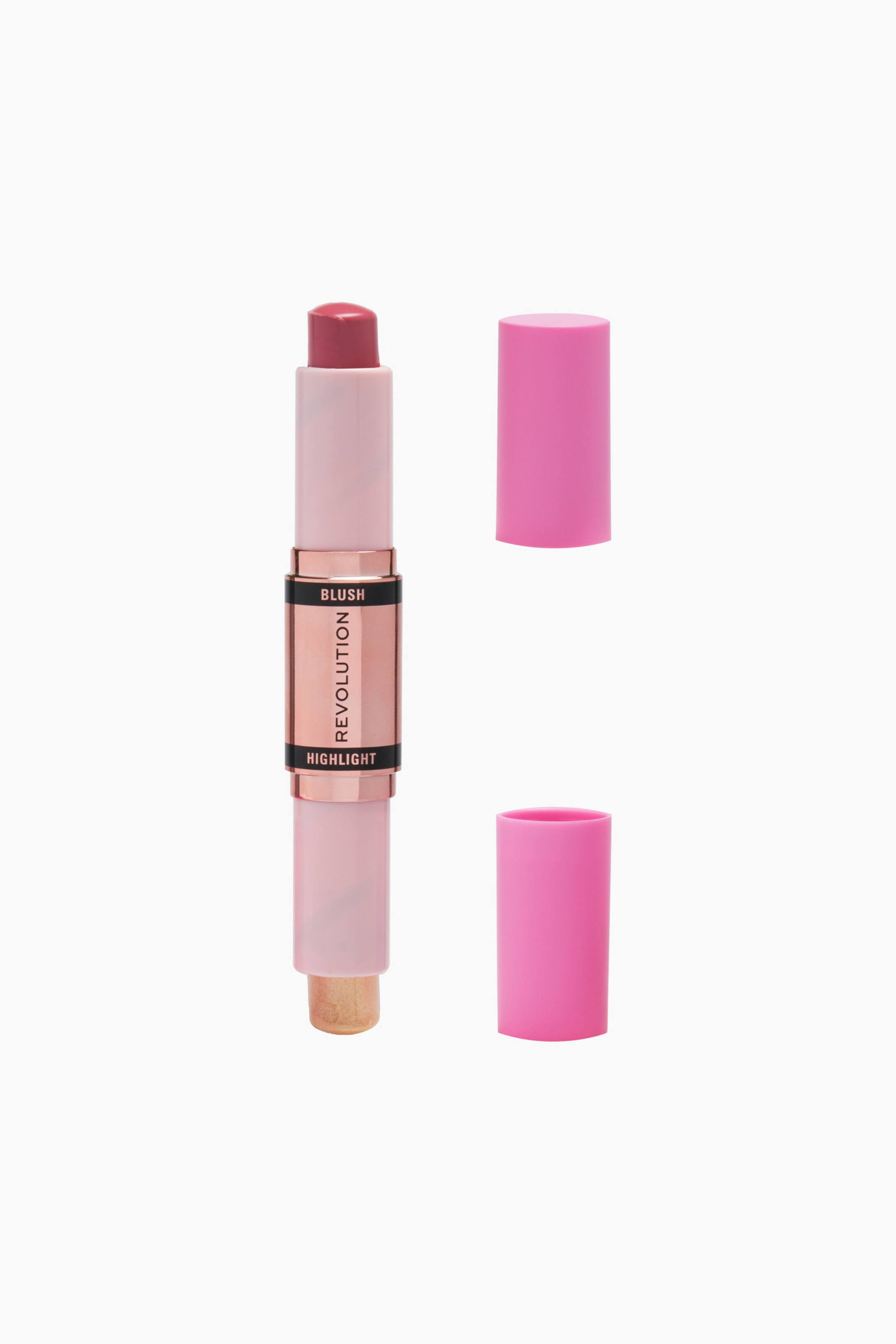 Größeres Bild ansehen: Ein doppelseitiger Blush- und Highlighter-Stick steht aufrecht und zeigt oben einen mauve-pinken Blush und unten einen schimmernden Champagner-Highlighter. Der roségoldene Mittelteil präsentiert zwischen schwarzen Bändern den Markennamen „REVOLUTION“, während zwei leuchtend pinke zylindrische Kappen rechts schwebend und abgenommen dargestellt sind.