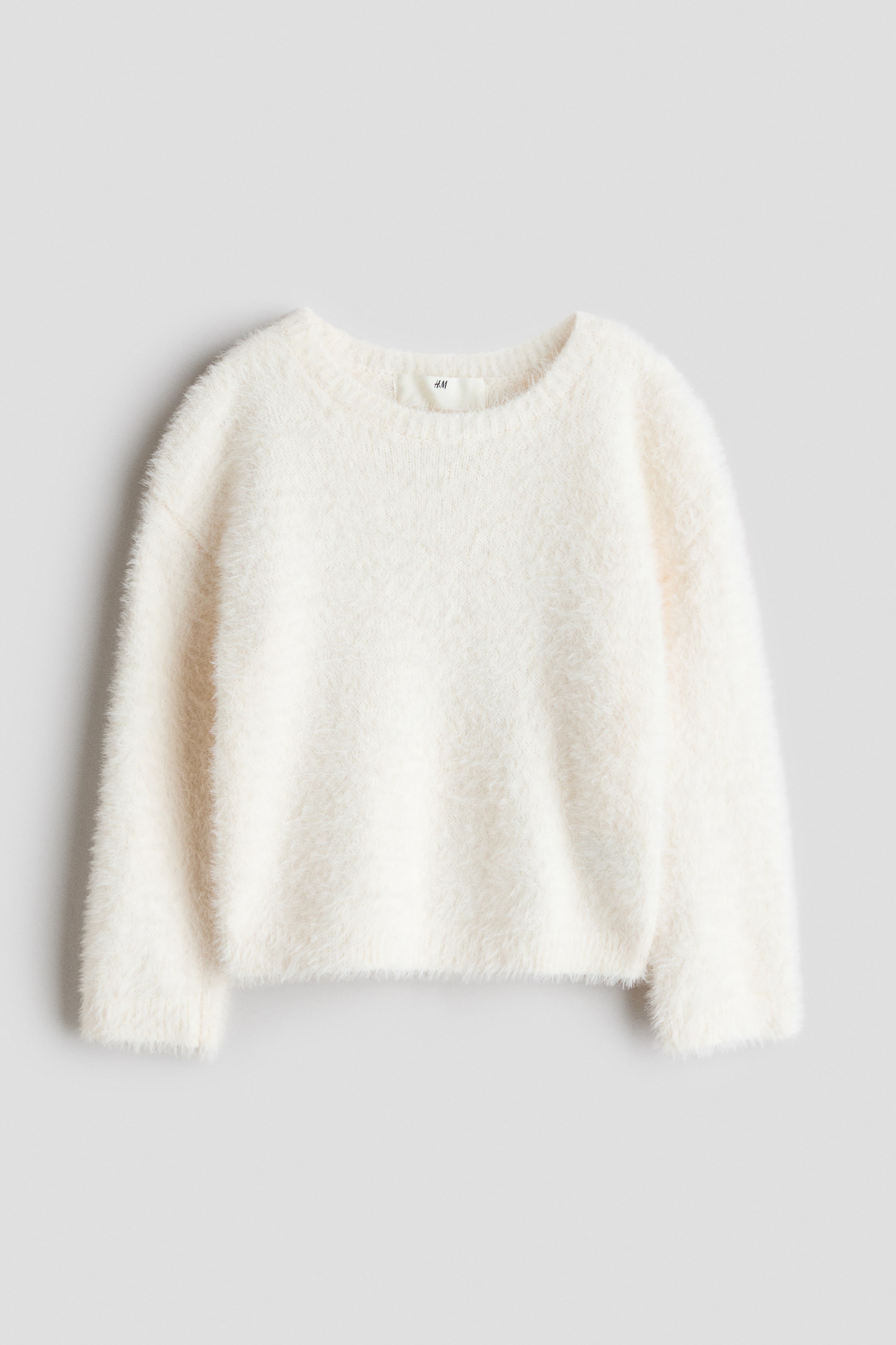 View larger image: A cream-coloured fuzzy pullover sweater is lying flat, featuring a crew neck, long sleeves, and a straight hem.