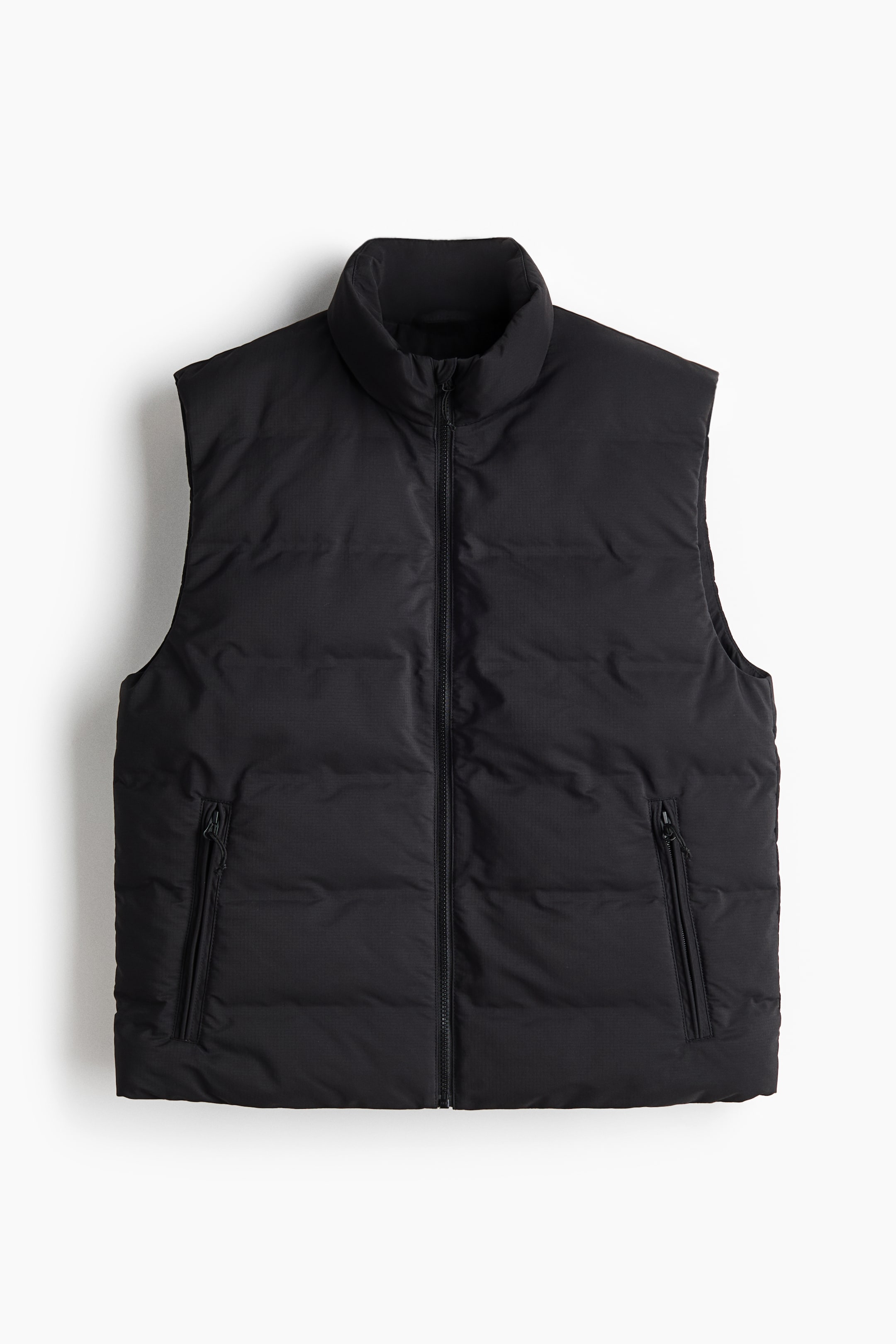 View larger image: The image showcases a black puffer vest viewed from the front, highlighting a stand-up collar and a full-length zipper running down the center. It features a padded, sleeveless design with two zippered pockets on the lower front.
