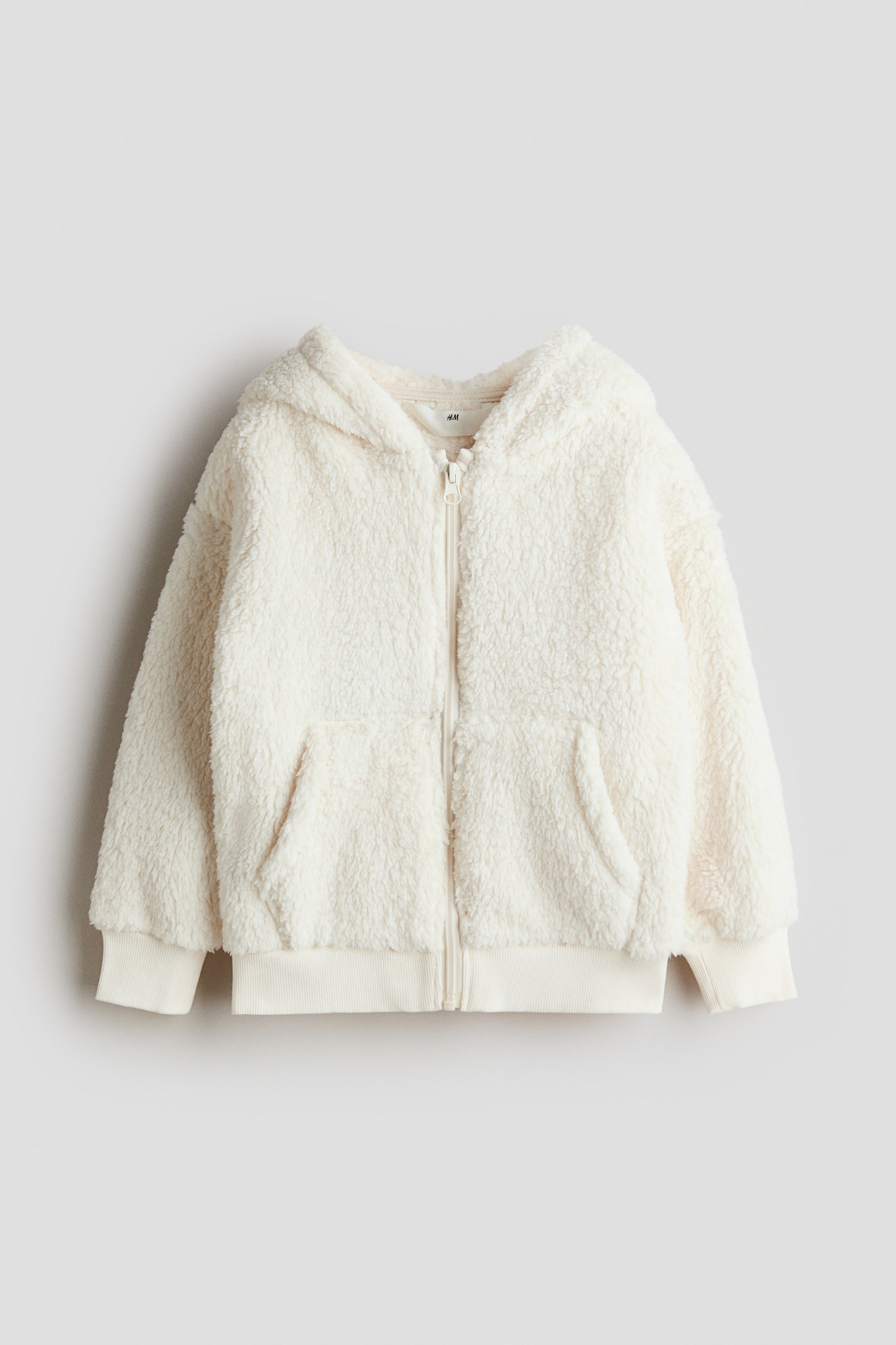 View larger image: A cream hooded jacket is displayed from the front, featuring a cosy texture, a full-length front zip, two patch pockets, and ribbed cuffs and hem.